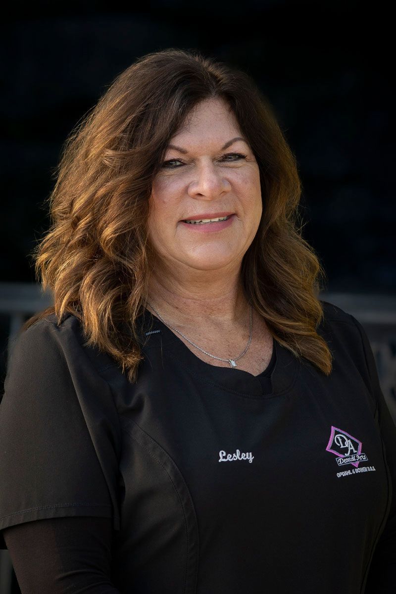 A woman in a black scrub top is smiling for the camera.