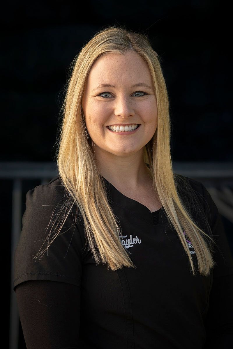 A woman in a black scrub top is smiling for the camera.