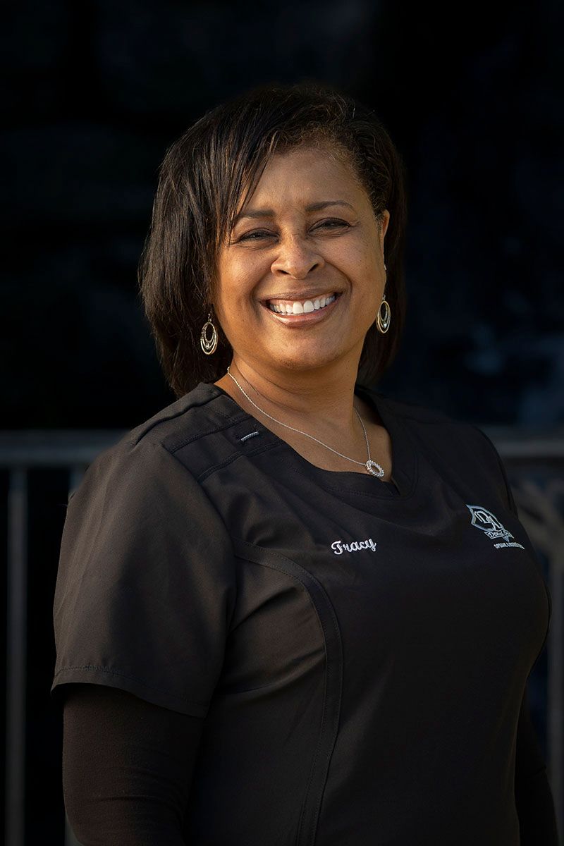A woman in a black scrub top is smiling for the camera.