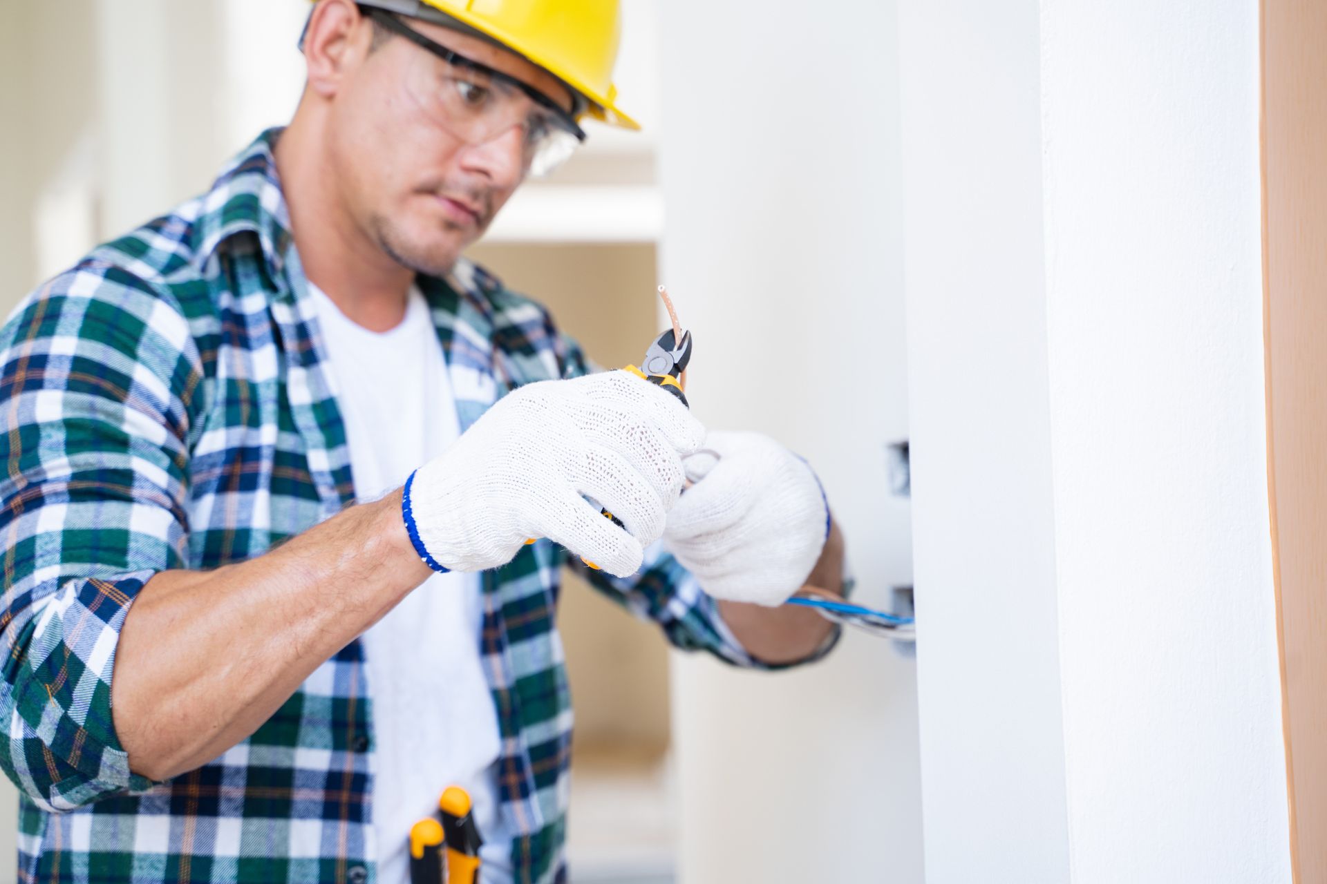 Residential electrician with tools working on wiring installation in home repair project. Residential electrician with tools working on wiring installation in home repair project.