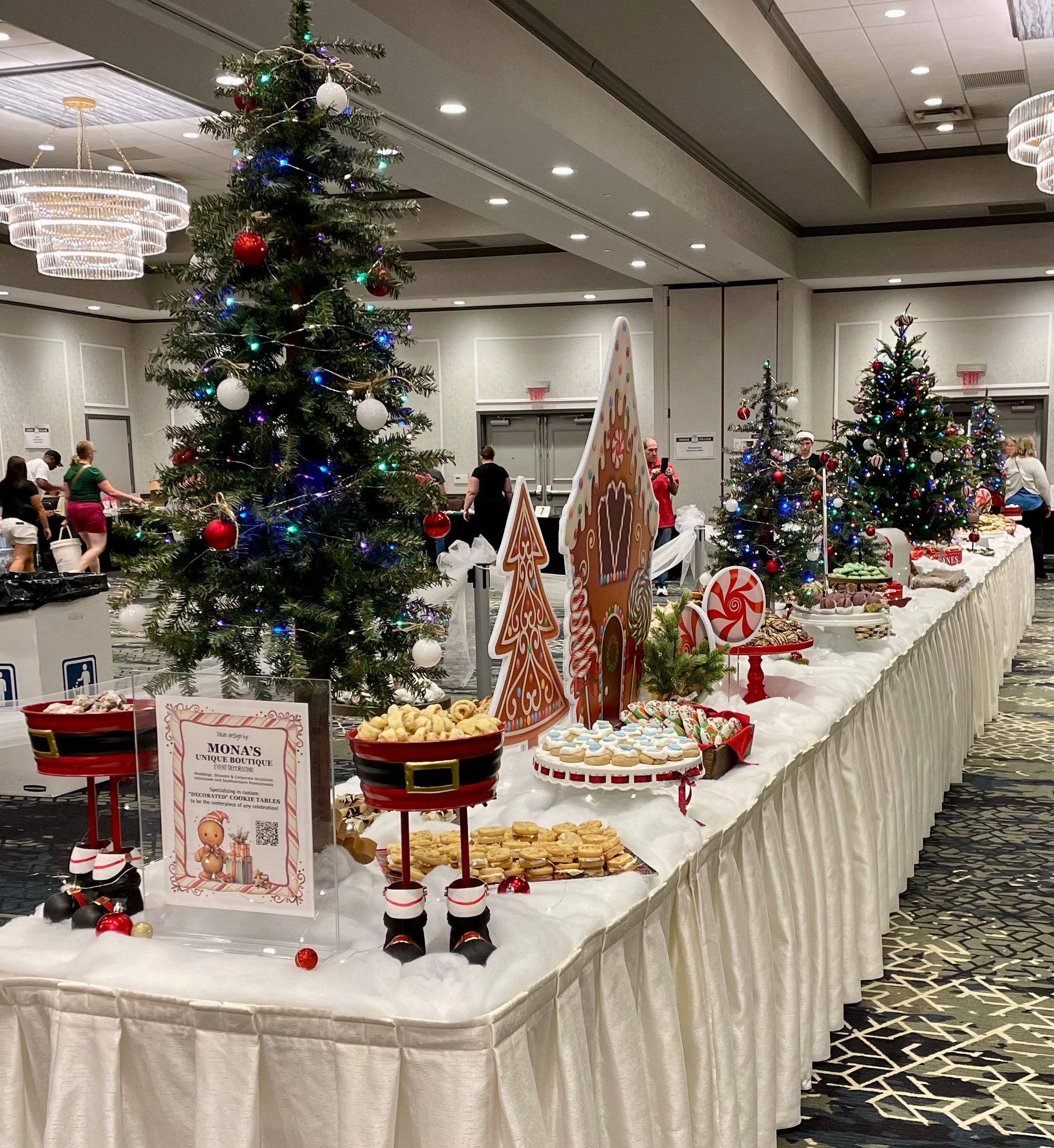 A dessert table featuring various pastries, including cookies and chocolates, with floral arrangements in a rustic setting.