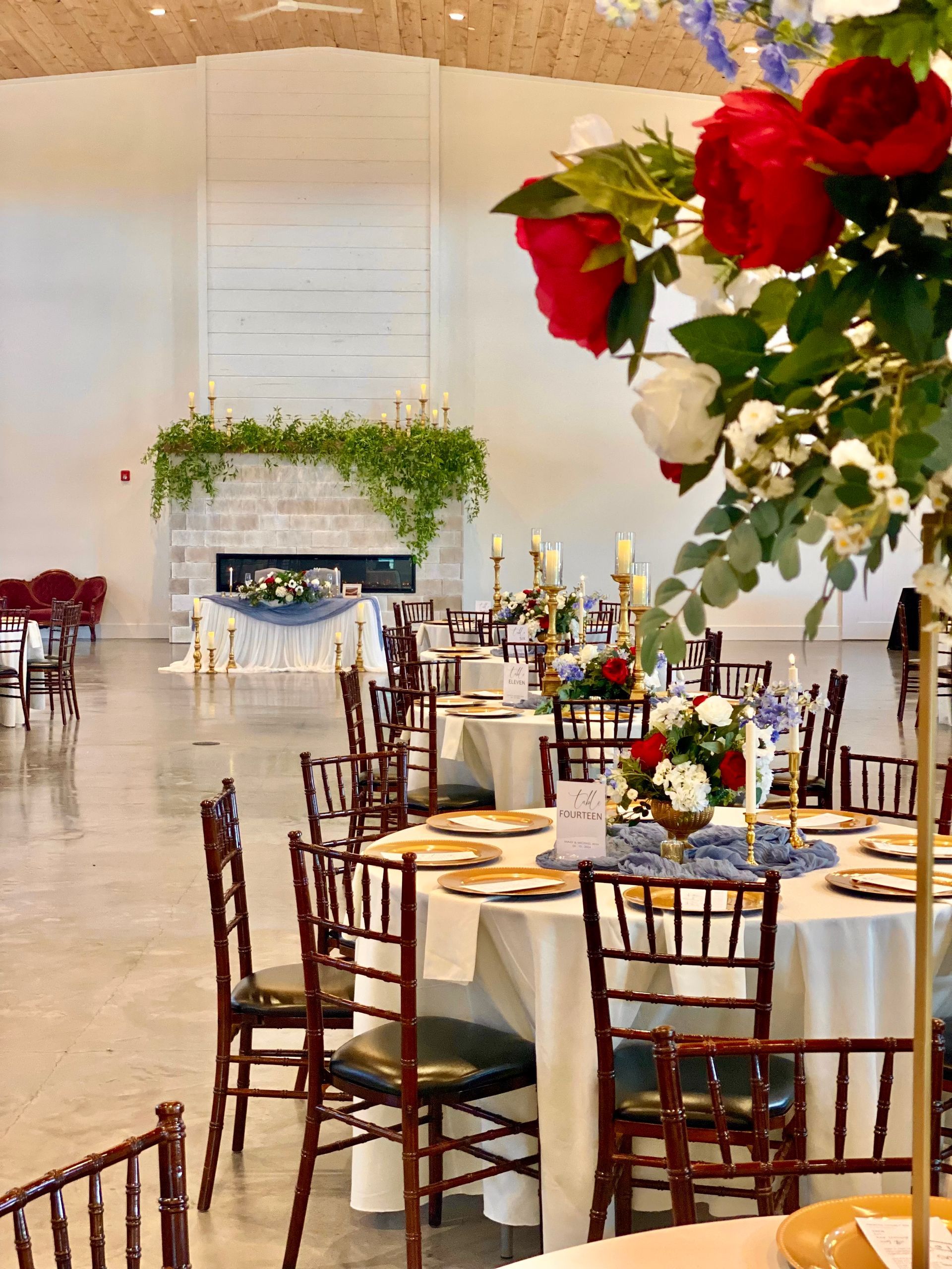Flowers with red and peach roses in front of a gold-framed mirror, reflecting a venue.