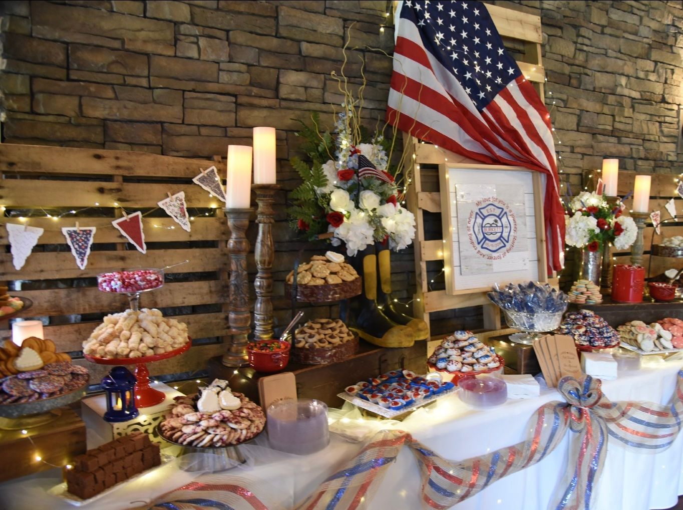 A patriotic dessert table with American flags, red, white, and blue decorations, and various cookies and treats.