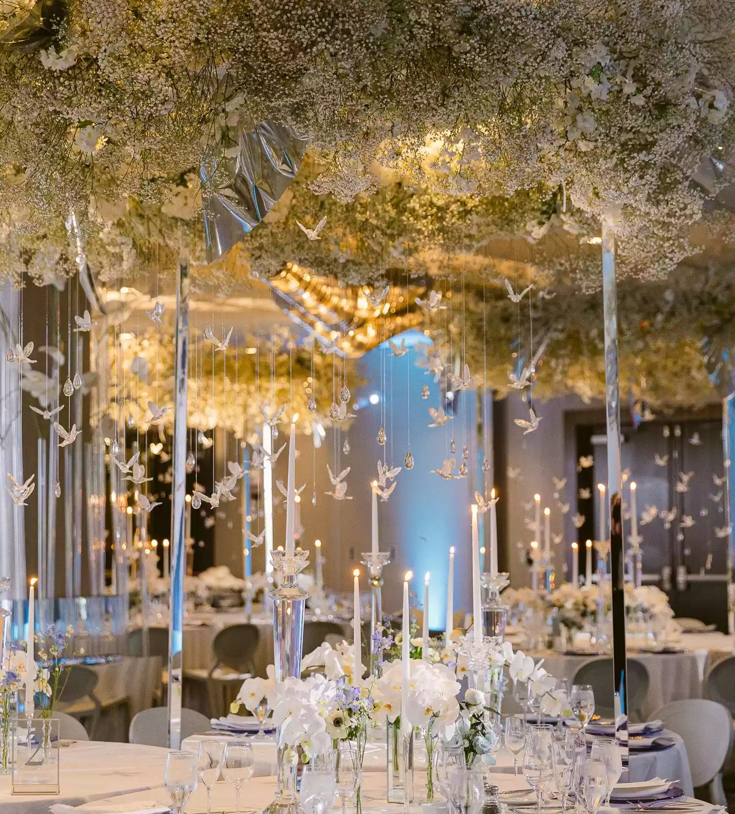 Wedding decor: Floral arrangements around a fireplace and a table with a pink lace tablecloth.
