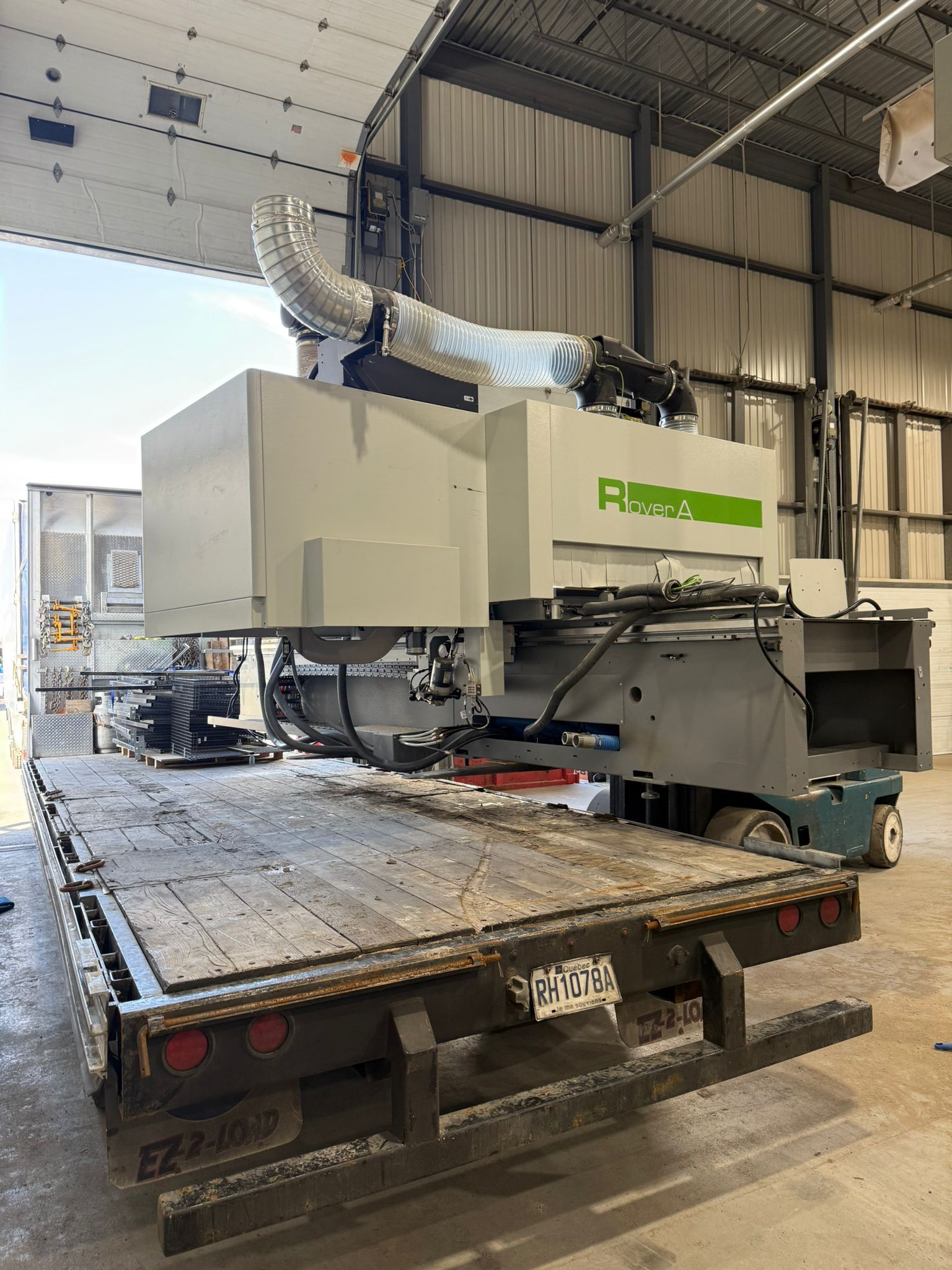 Large industrial machine mounted on a flatbed truck inside a warehouse.
