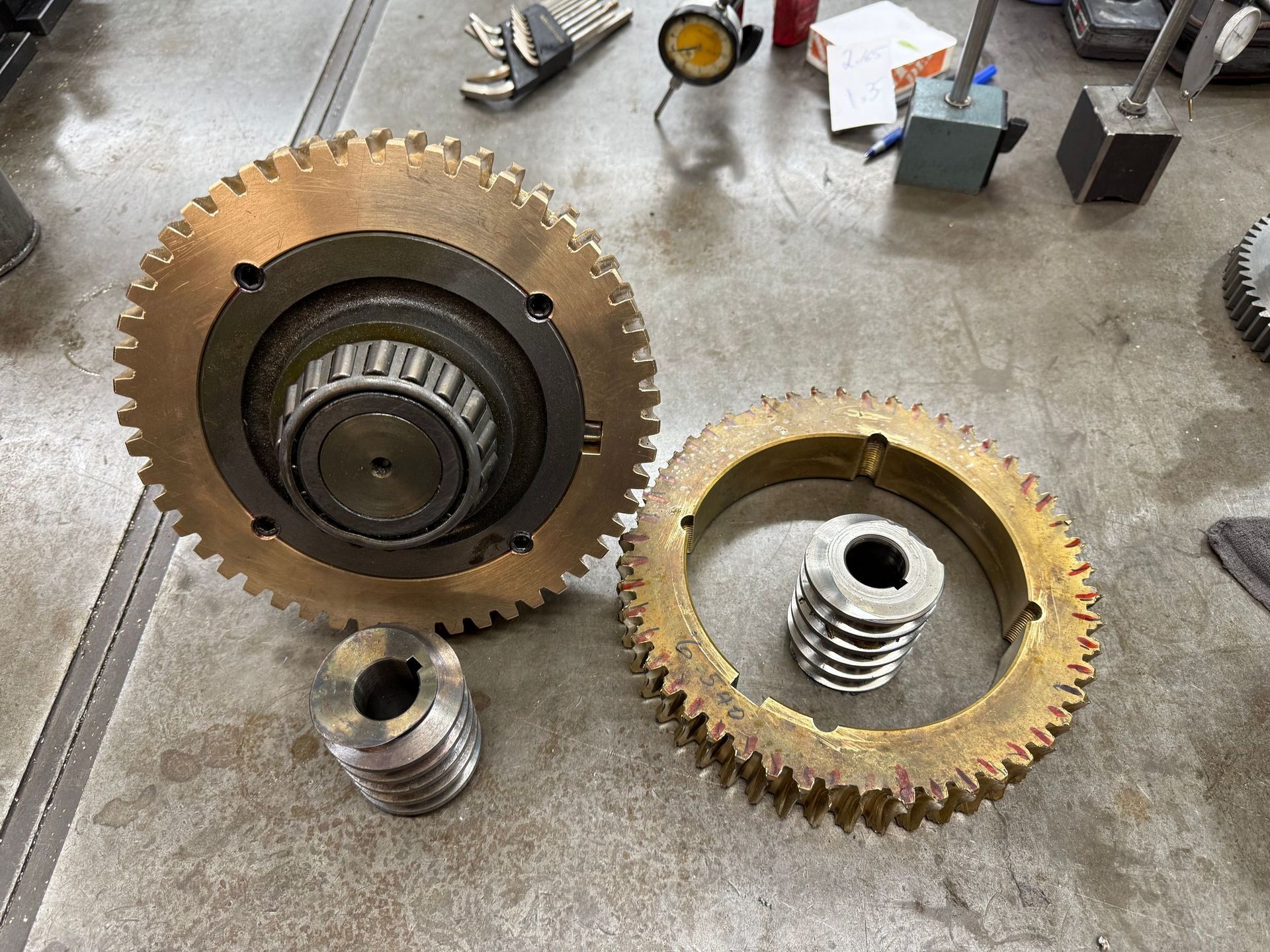 Large bronze gears and worm gears on a workshop floor.