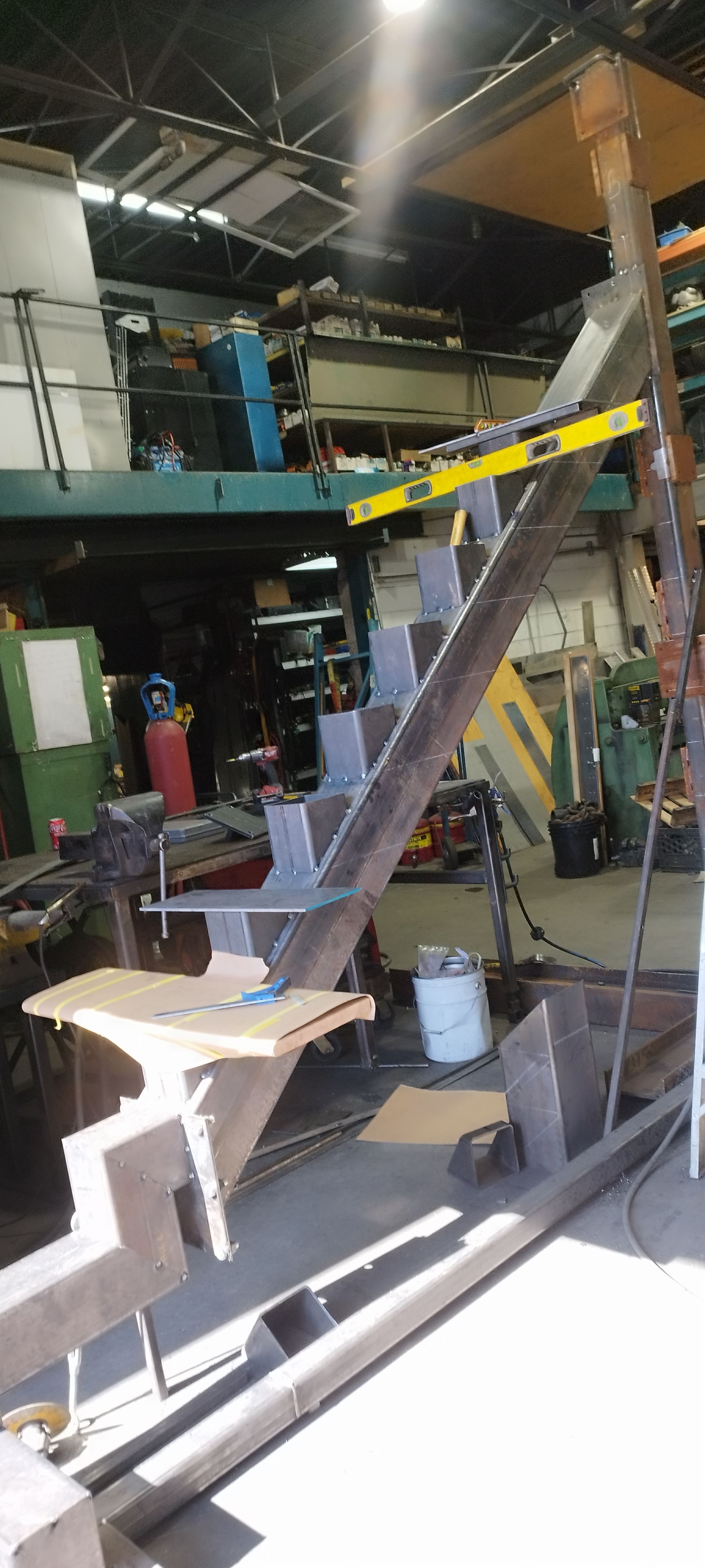 Metal fabrication workshop, metal beams and welding, level, and workspace.