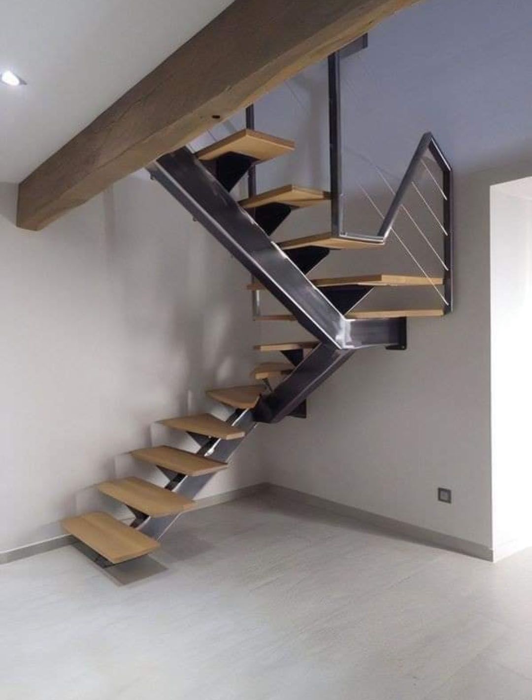 Modern staircase with steel frame and wooden steps in a room with grey walls.