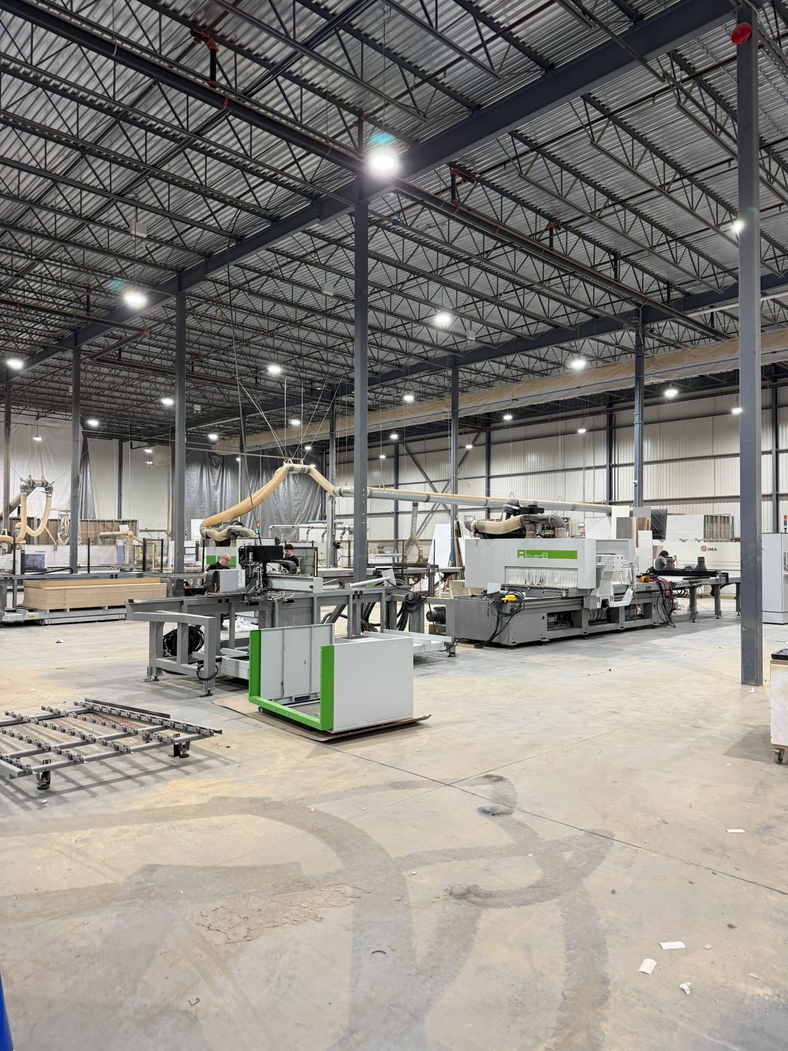 Large industrial warehouse with machinery, high ceilings, and metal support beams.