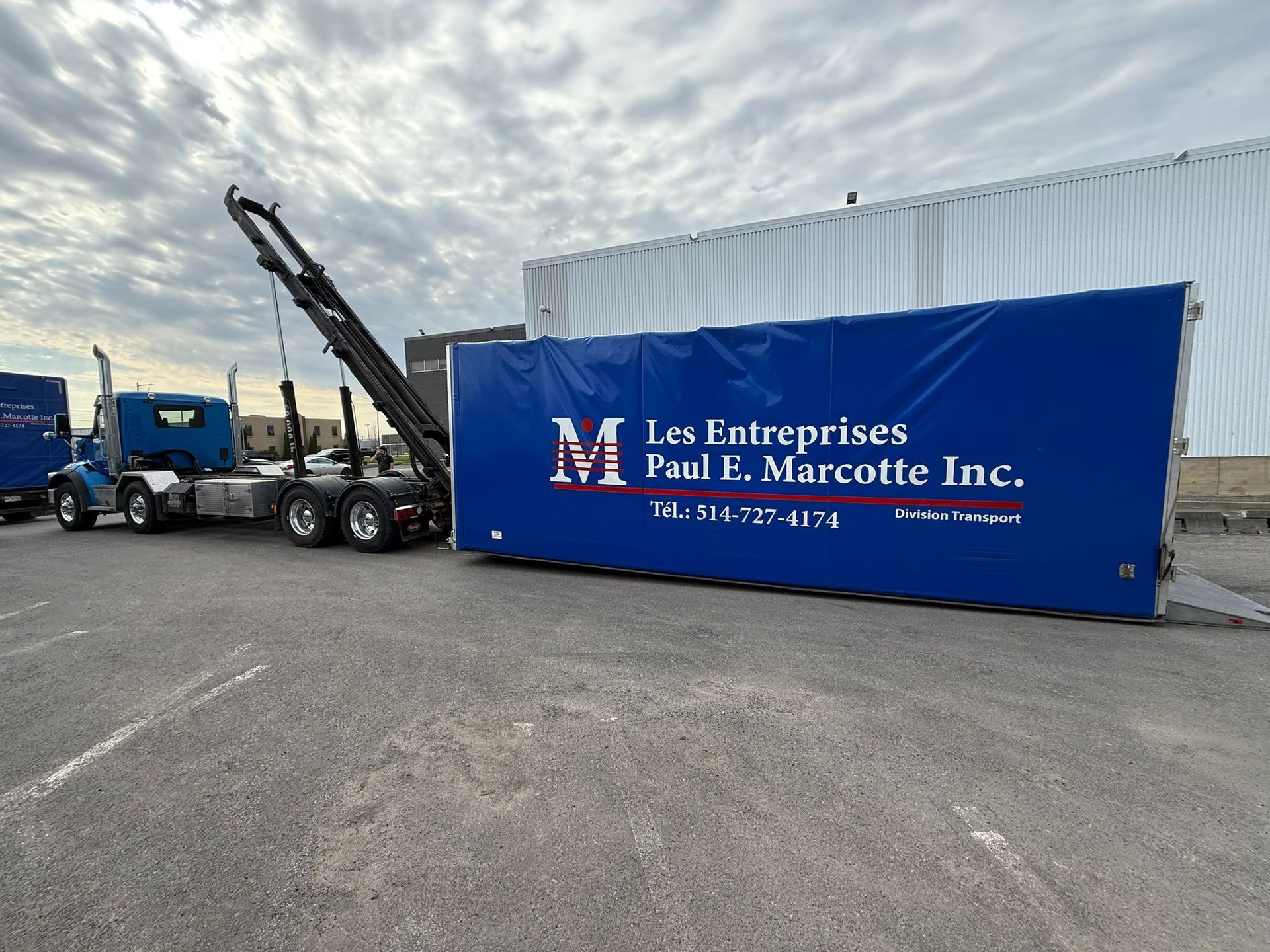 Blue truck lifting a blue container with company logo 
