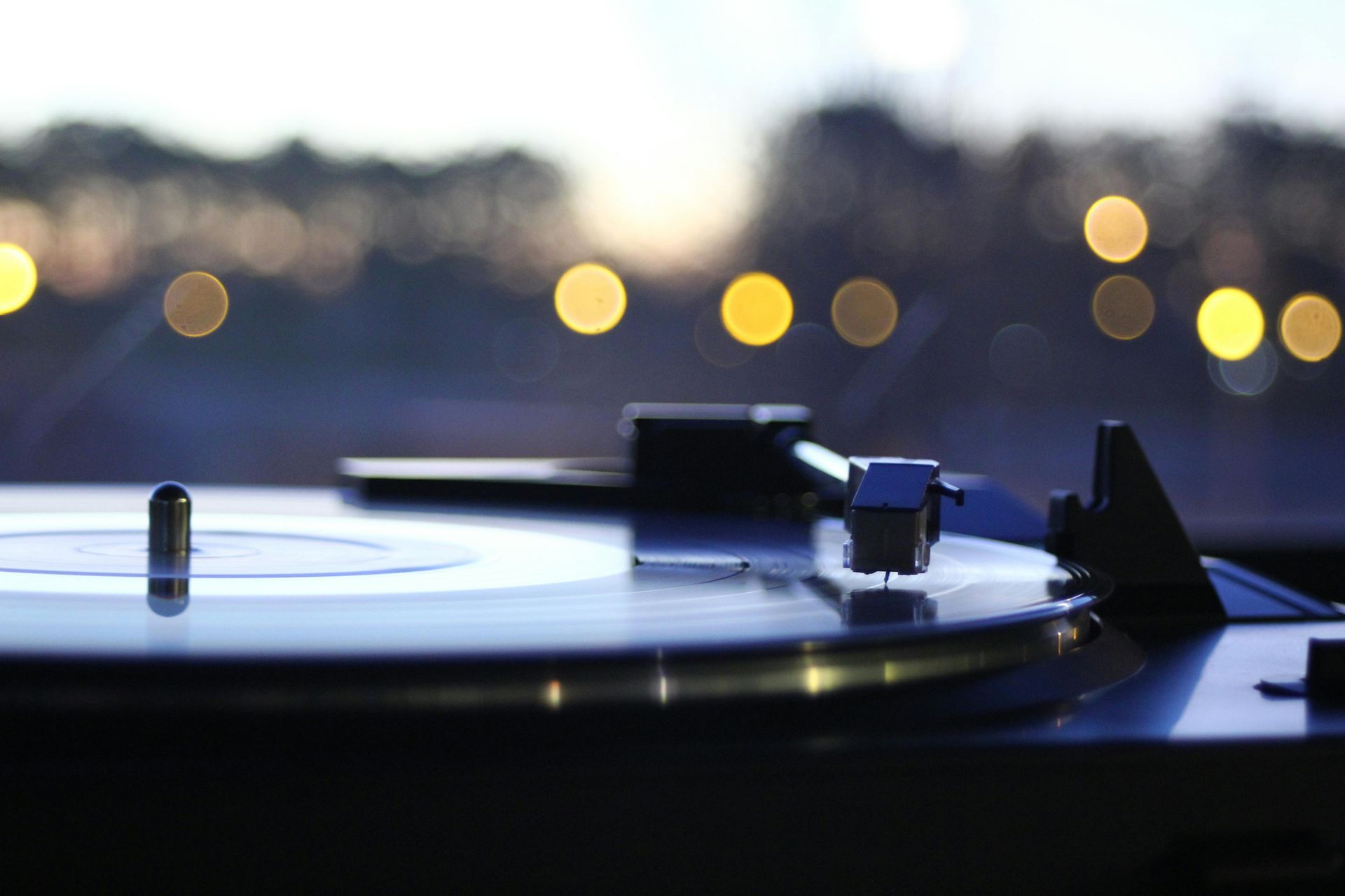 Turntable playing a record; out-of-focus bokeh lights in the background.