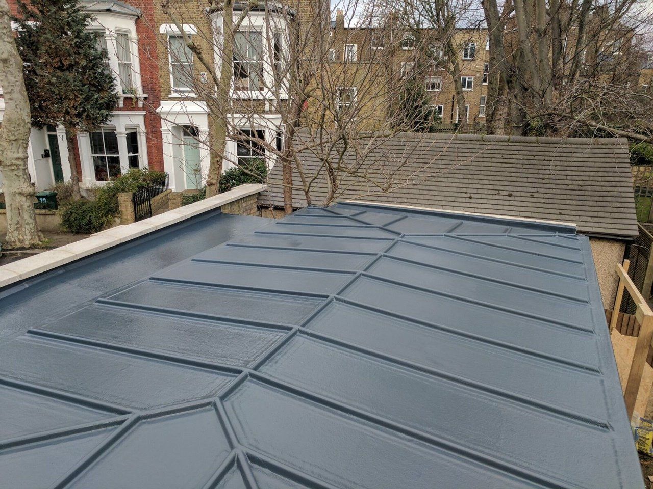 A roof of a house with a blue roof and trees in the background.