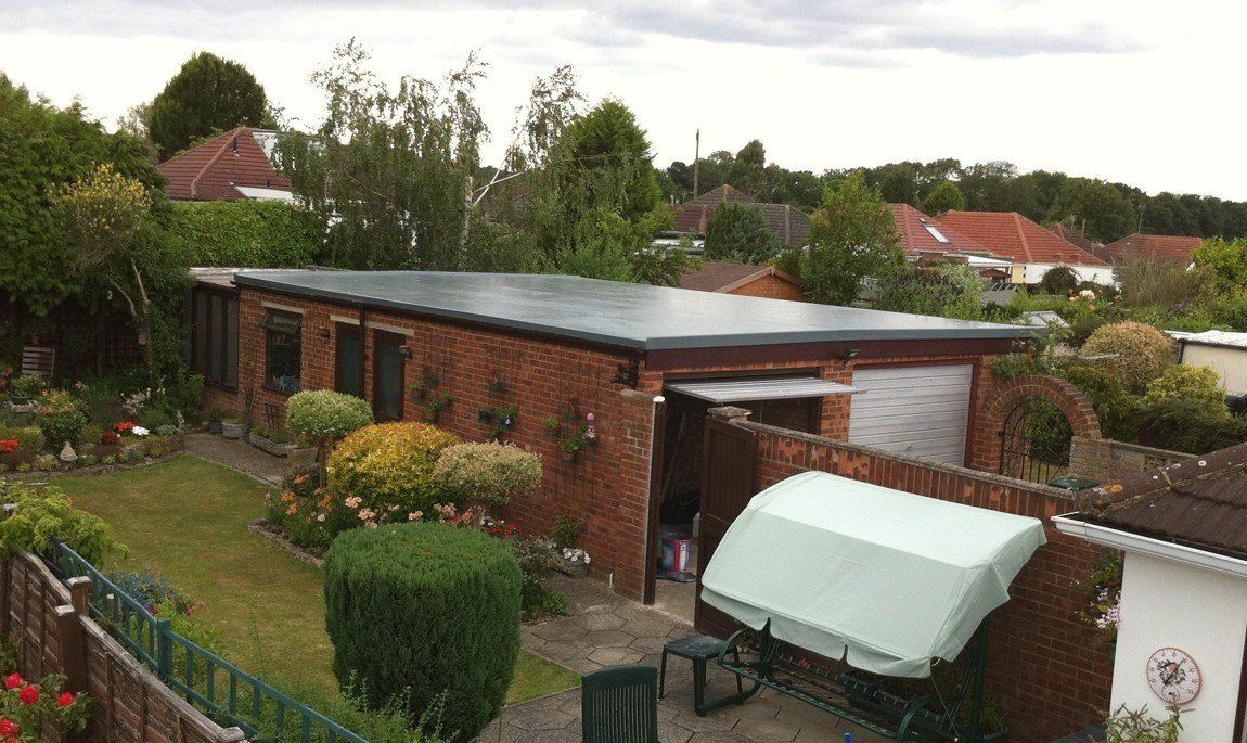 An aerial view of a brick house with a green umbrella in the backyard.