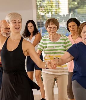 People dancing in a bright studio, holding hands in a group exercise class