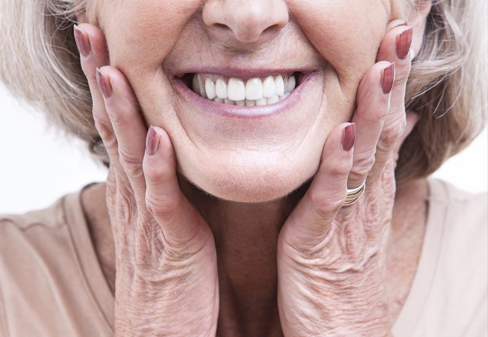 A Smiling Person With Hands Touching Their Cheeks, Highlighting Dental Work — Smiles on Hudson In Lake Macquarie, NSW