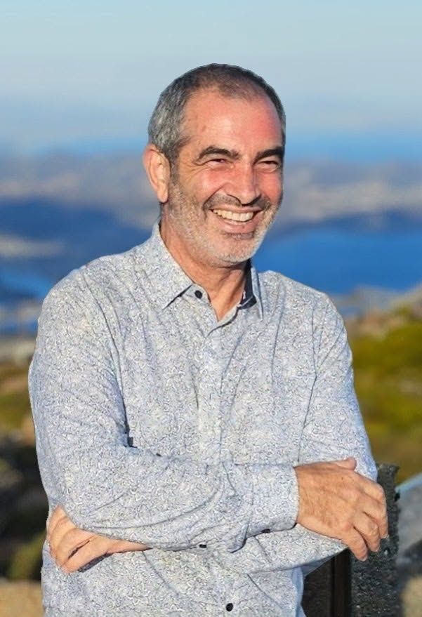 Man with graying hair smiling, arms crossed, outdoors with mountains in background — Smiles on Hudson In Hamilton, NSW
