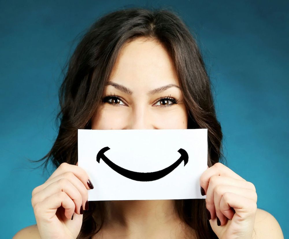 Woman Holding a Card With a Drawn Smile, Blue Background — Smiles on Hudson In Hamilton, NSW