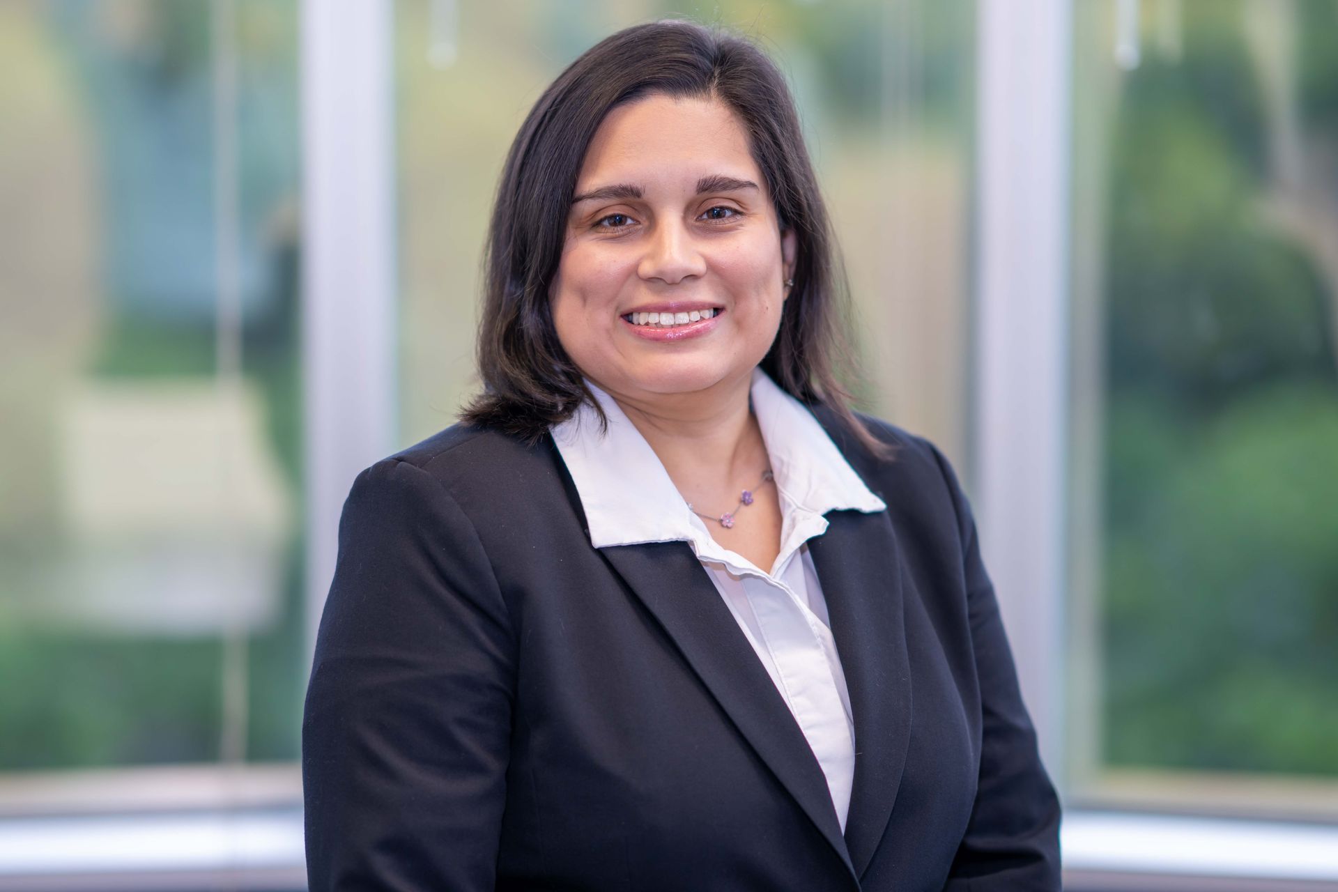 A woman in a suit is sitting at a desk in front of a computer.