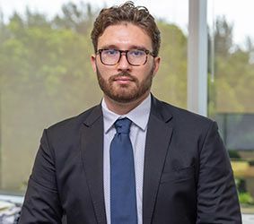 A man in a suit and tie is standing in front of a window.