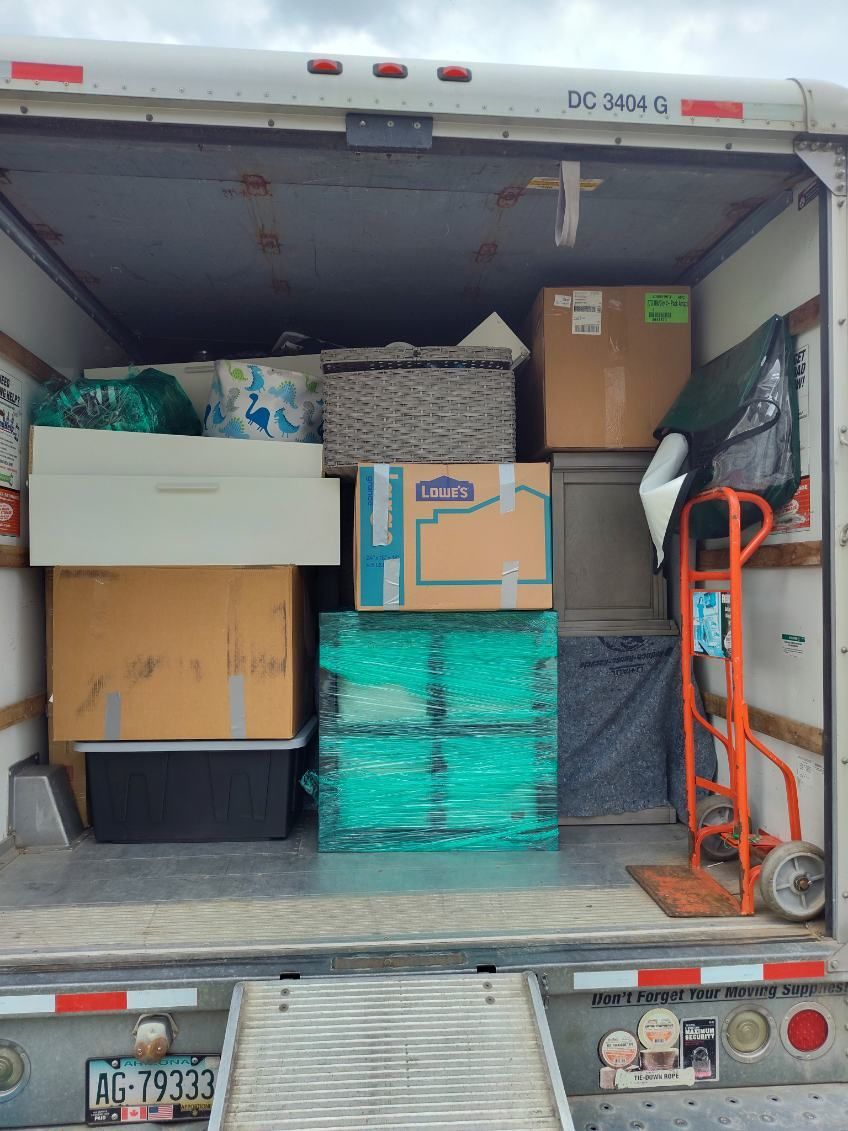 The back of a moving truck filled with boxes and a dolly