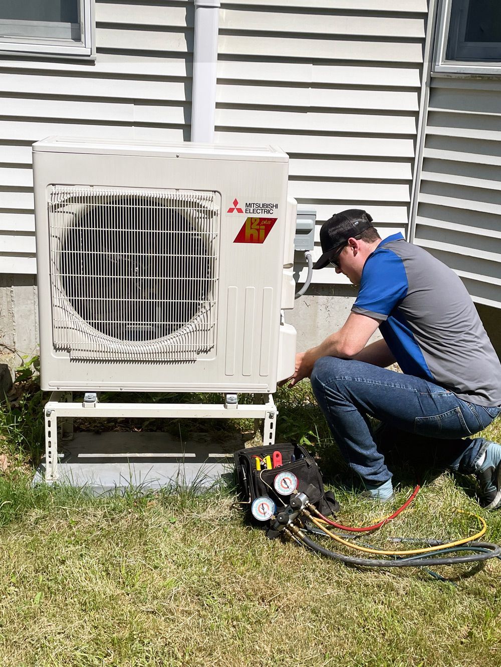A man is working on an air conditioner outside of a house.