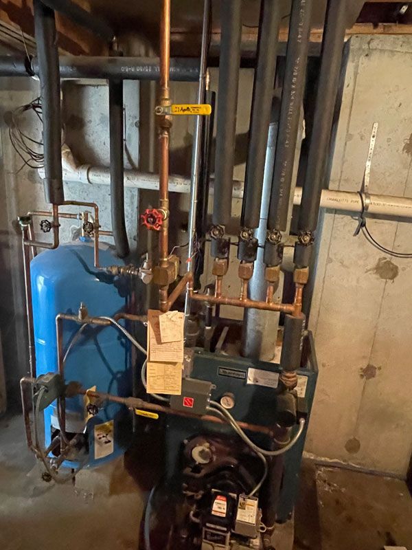 A well tank in a basement with a plumbing manifold.