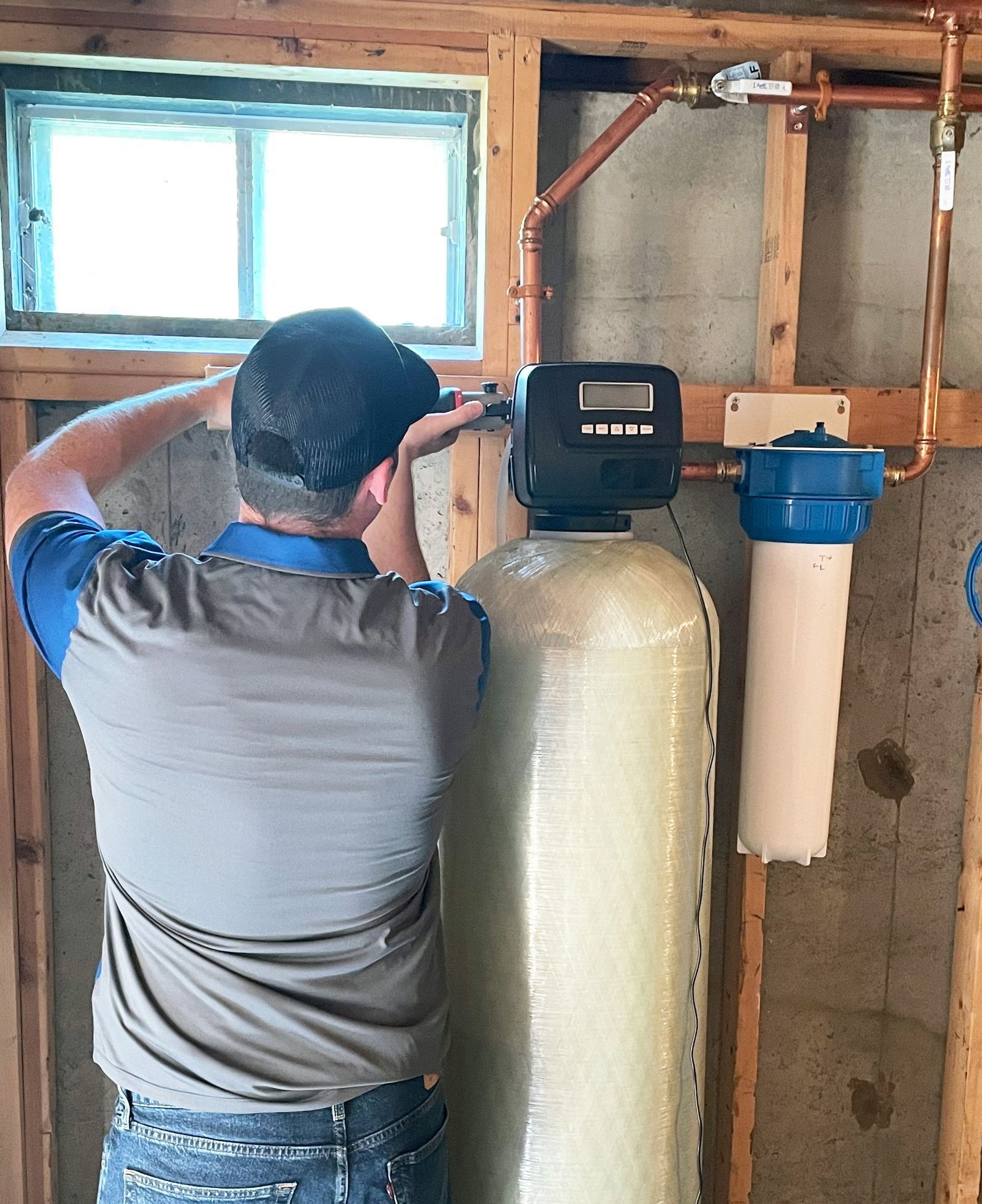 A man is working on a water filter in a basement.