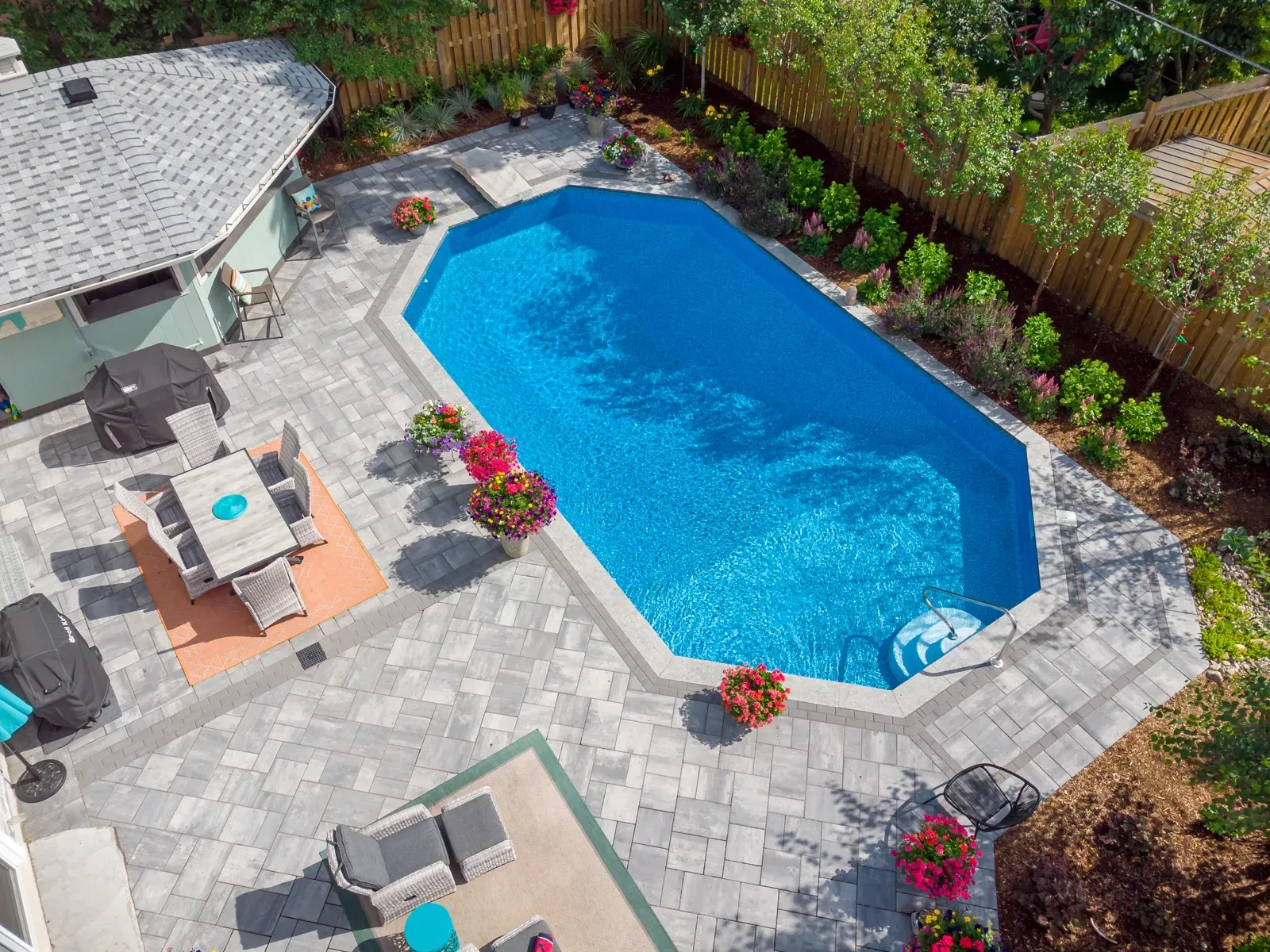 An aerial view of a large swimming pool in a backyard surrounded by patio furniture.