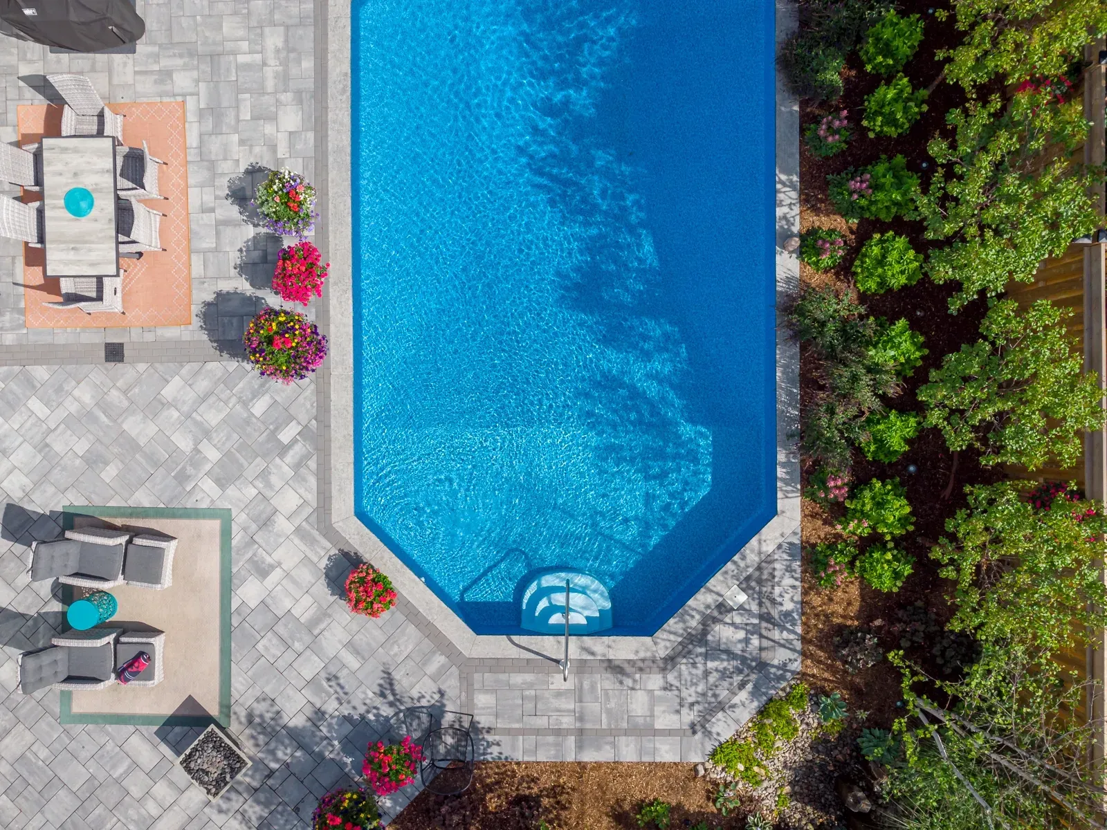 An aerial view of a swimming pool with a table and chairs in the backyard.