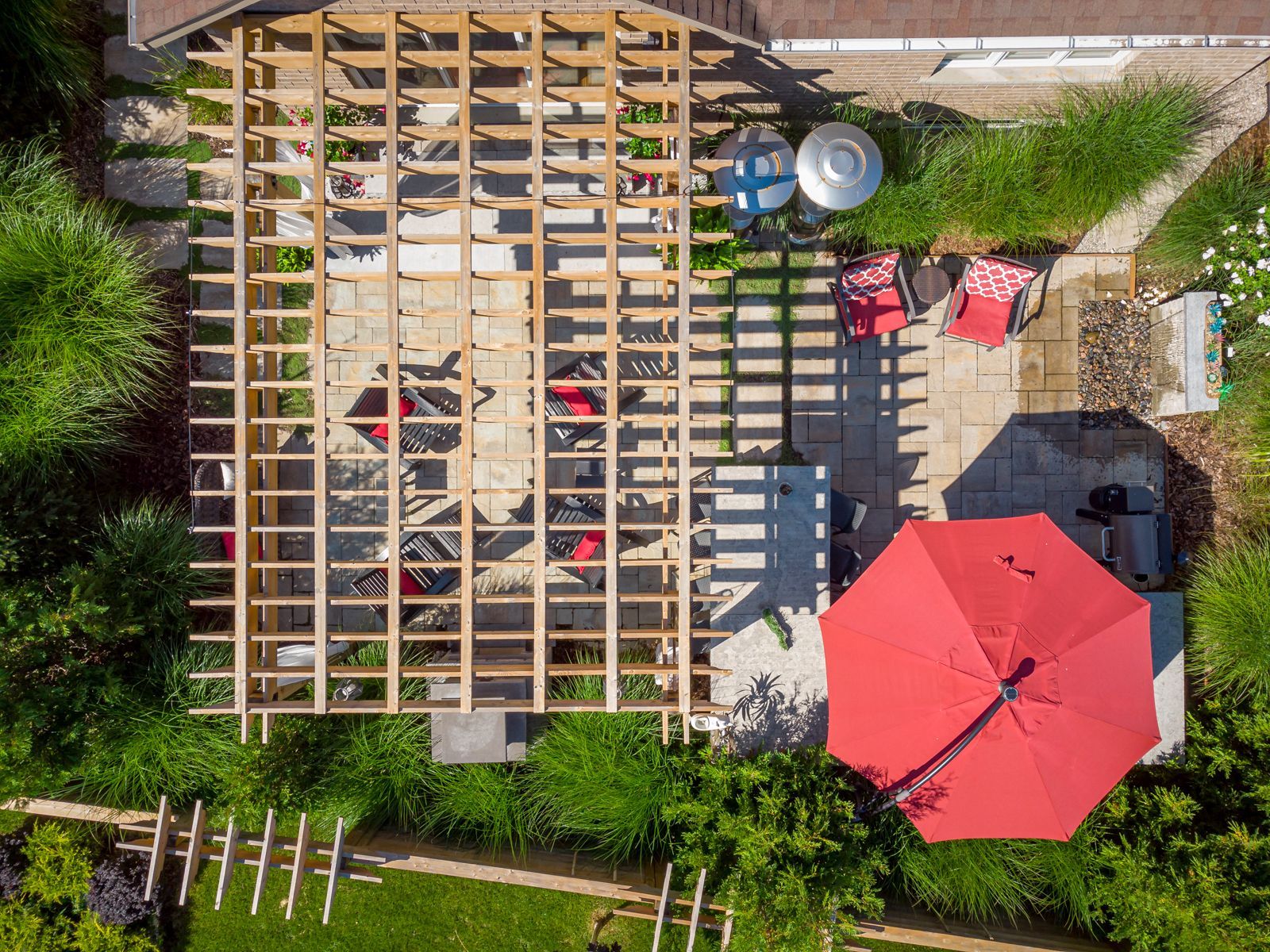 An aerial view of a patio with a red umbrella and a pergola.