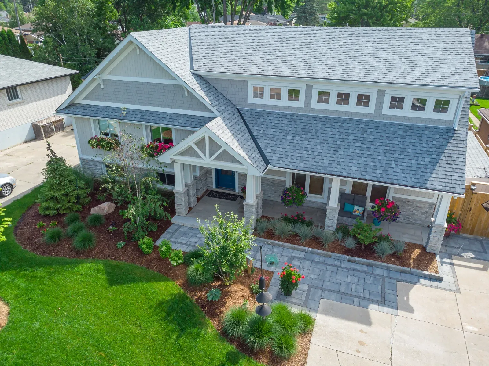 An aerial view of a house with a blue roof and a lush green lawn.