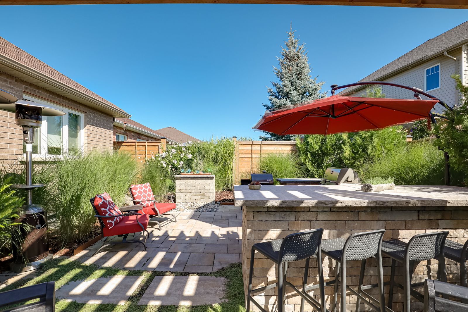 There is a red umbrella in the backyard of a house.
