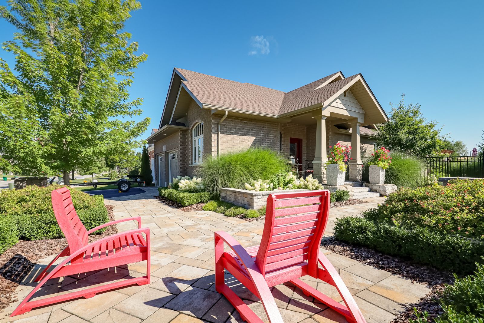 Two red chairs are sitting on a patio in front of a house.