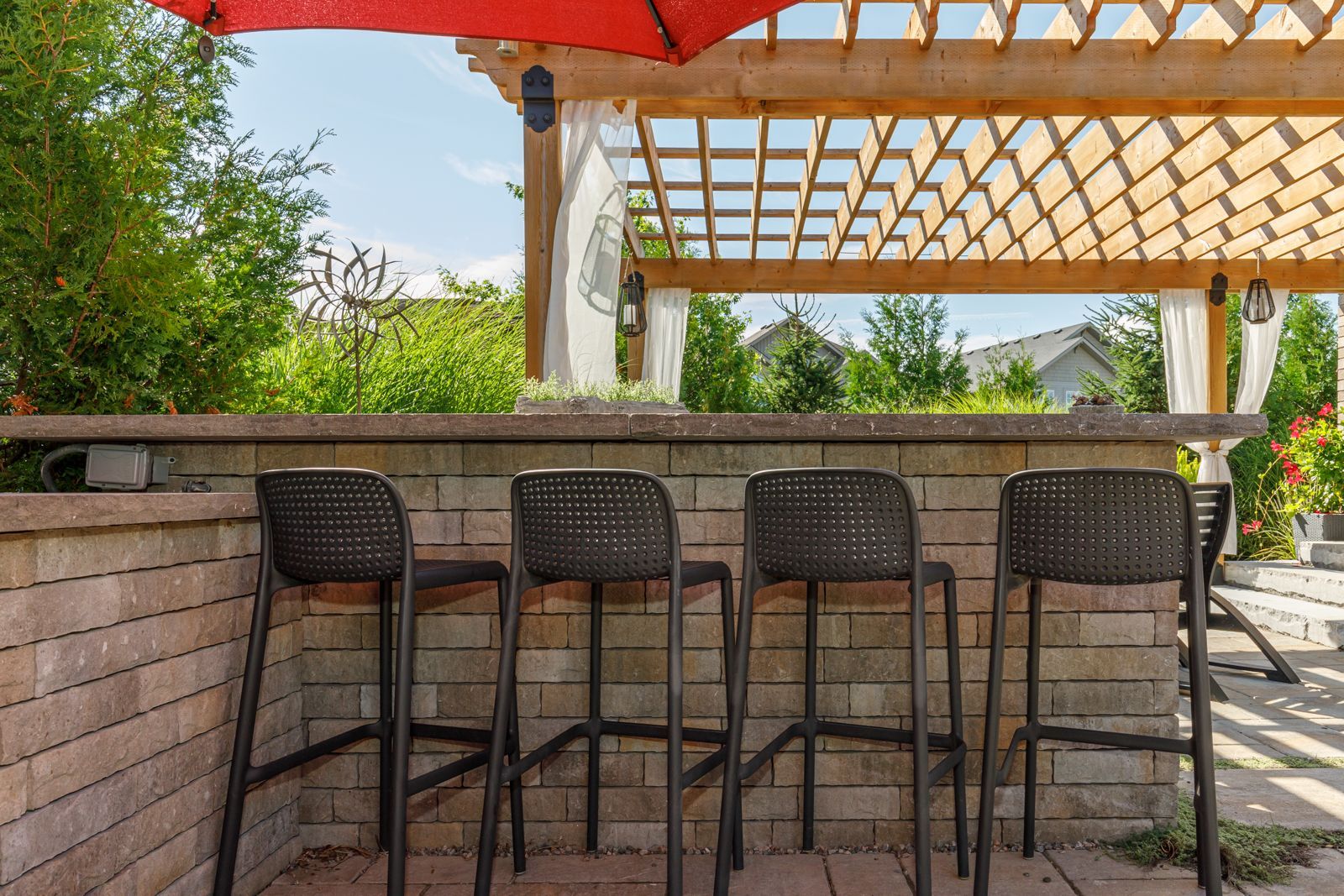 A patio with a bar and chairs under a pergola.