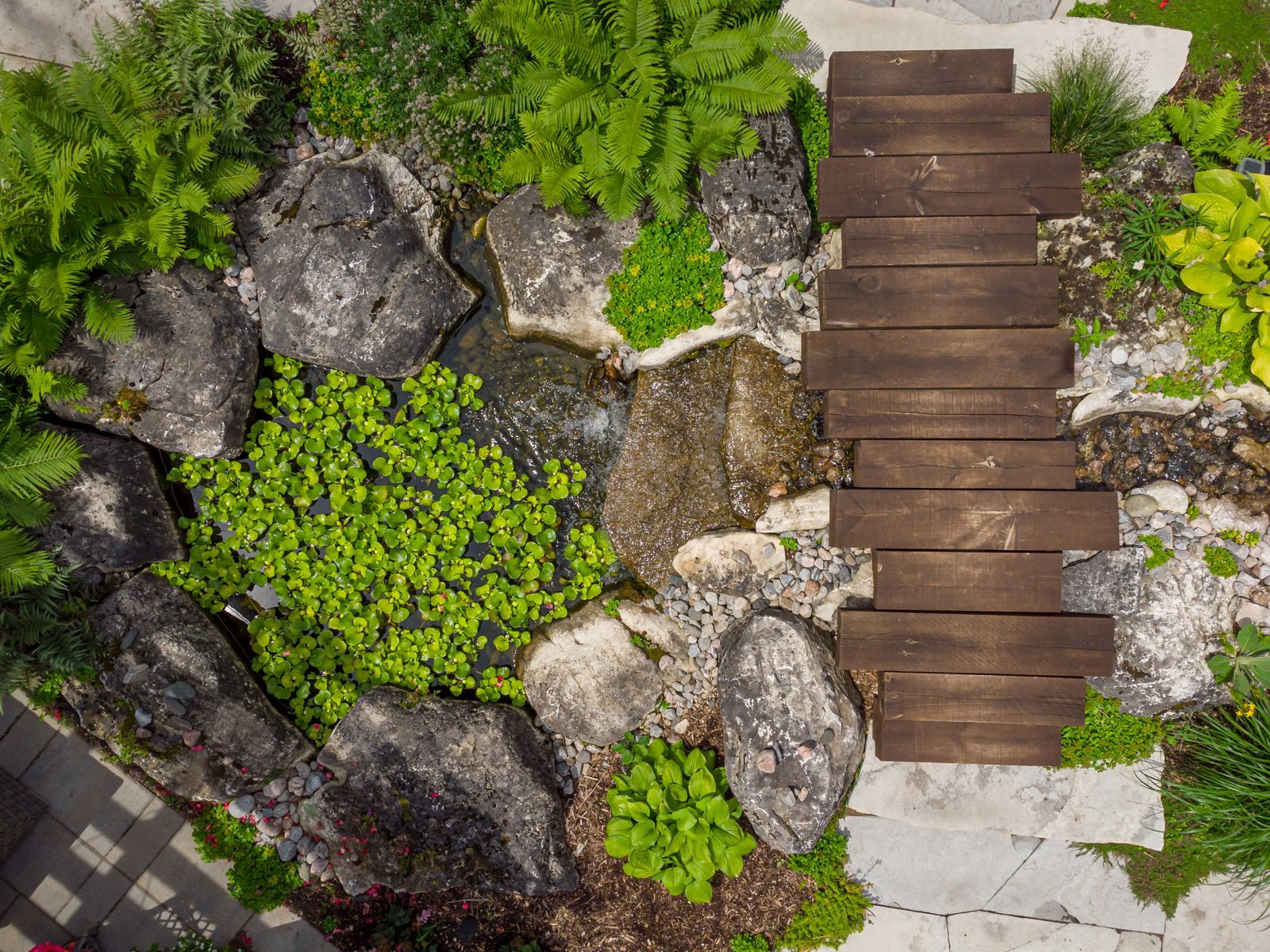 An aerial view of a wooden bridge surrounded by rocks and plants.