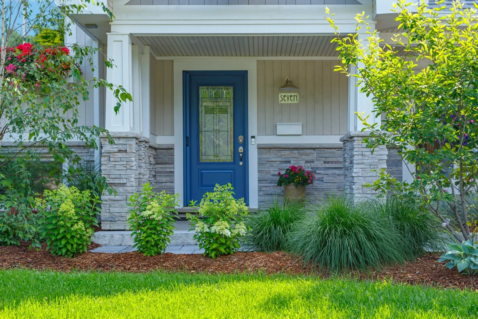 The front of a house with a blue door and a lush green lawn.