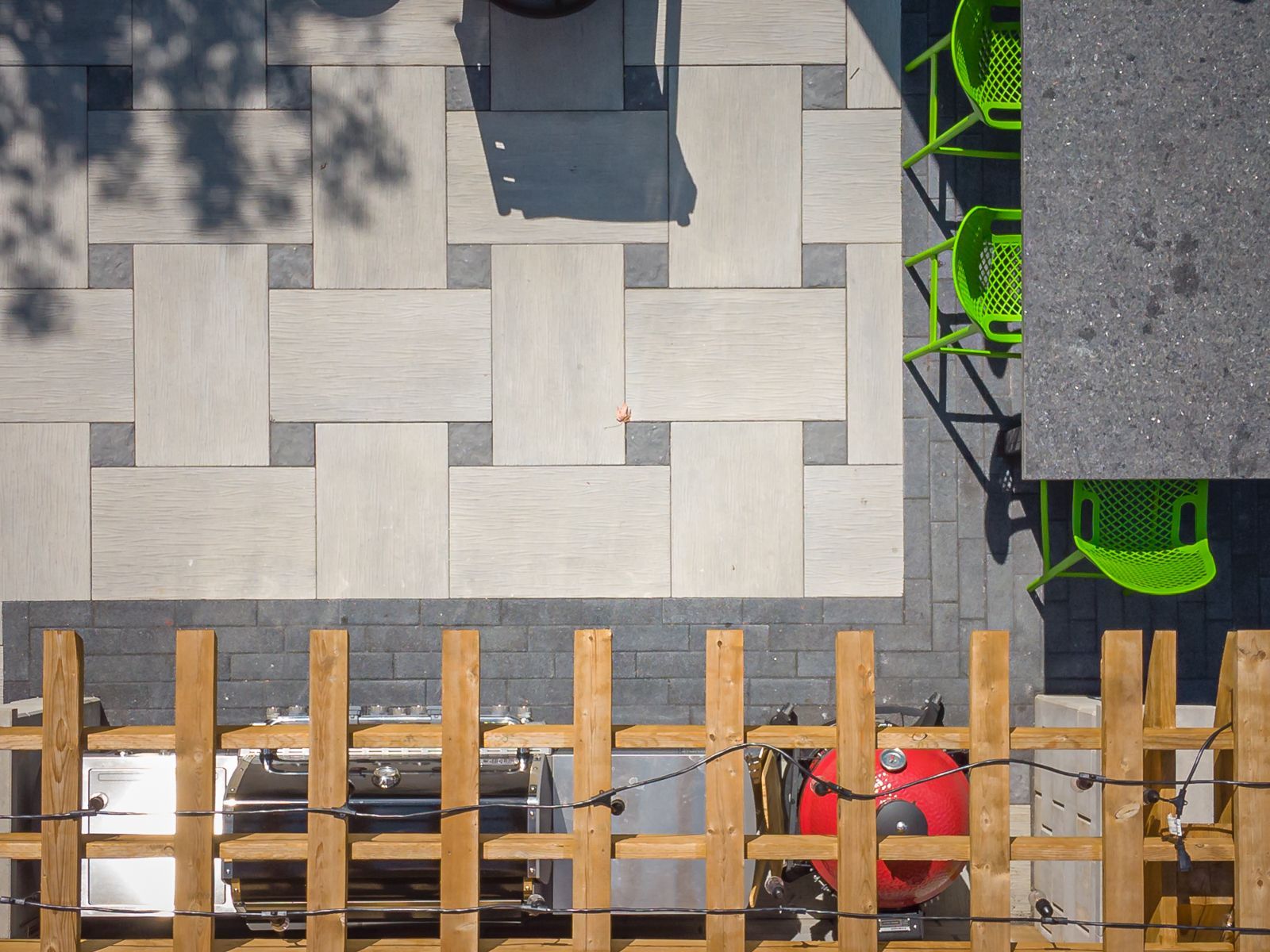 An aerial view of a patio with a wooden fence and a grill.