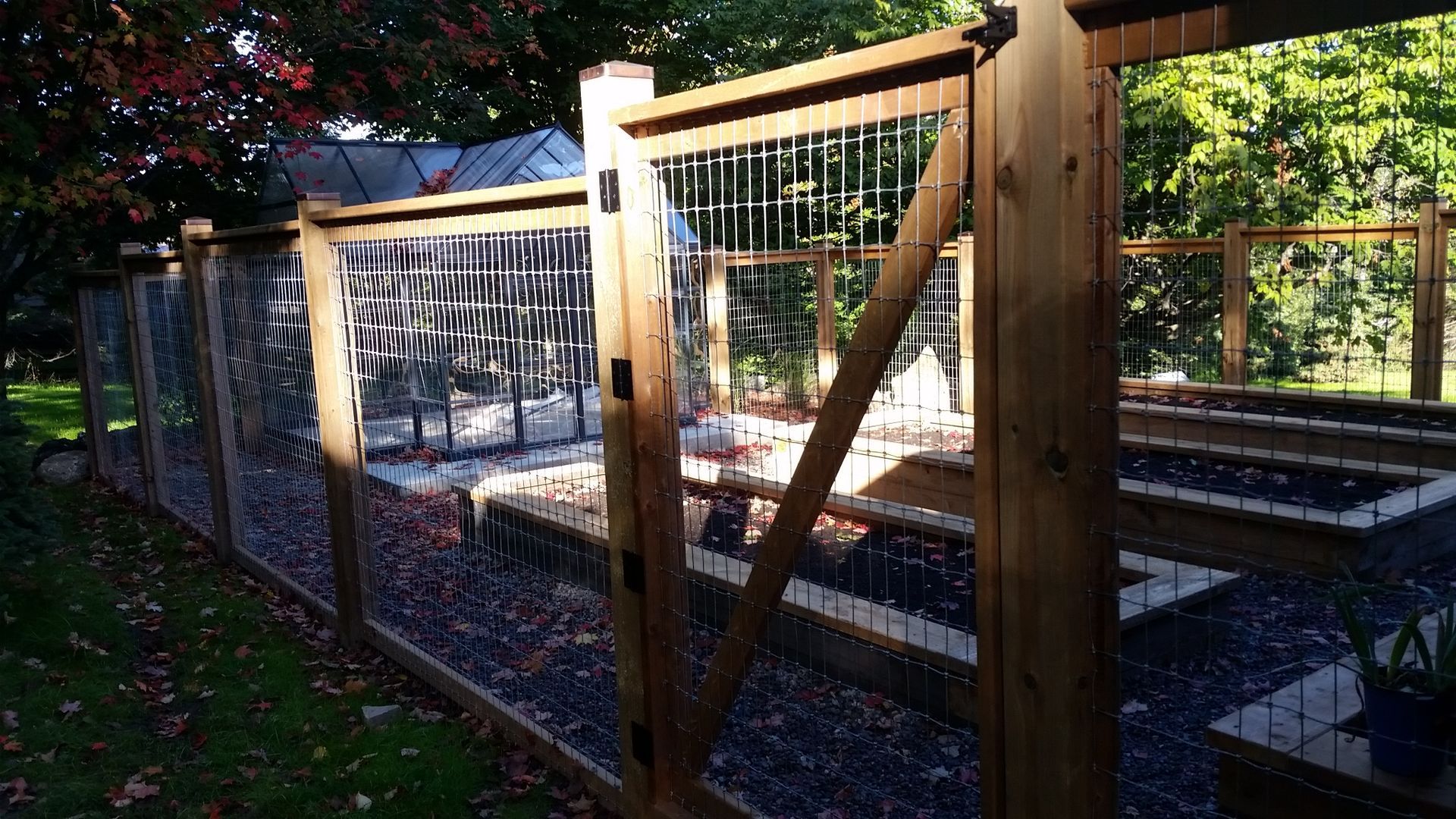 A wooden fence with a wire fence surrounding a garden.