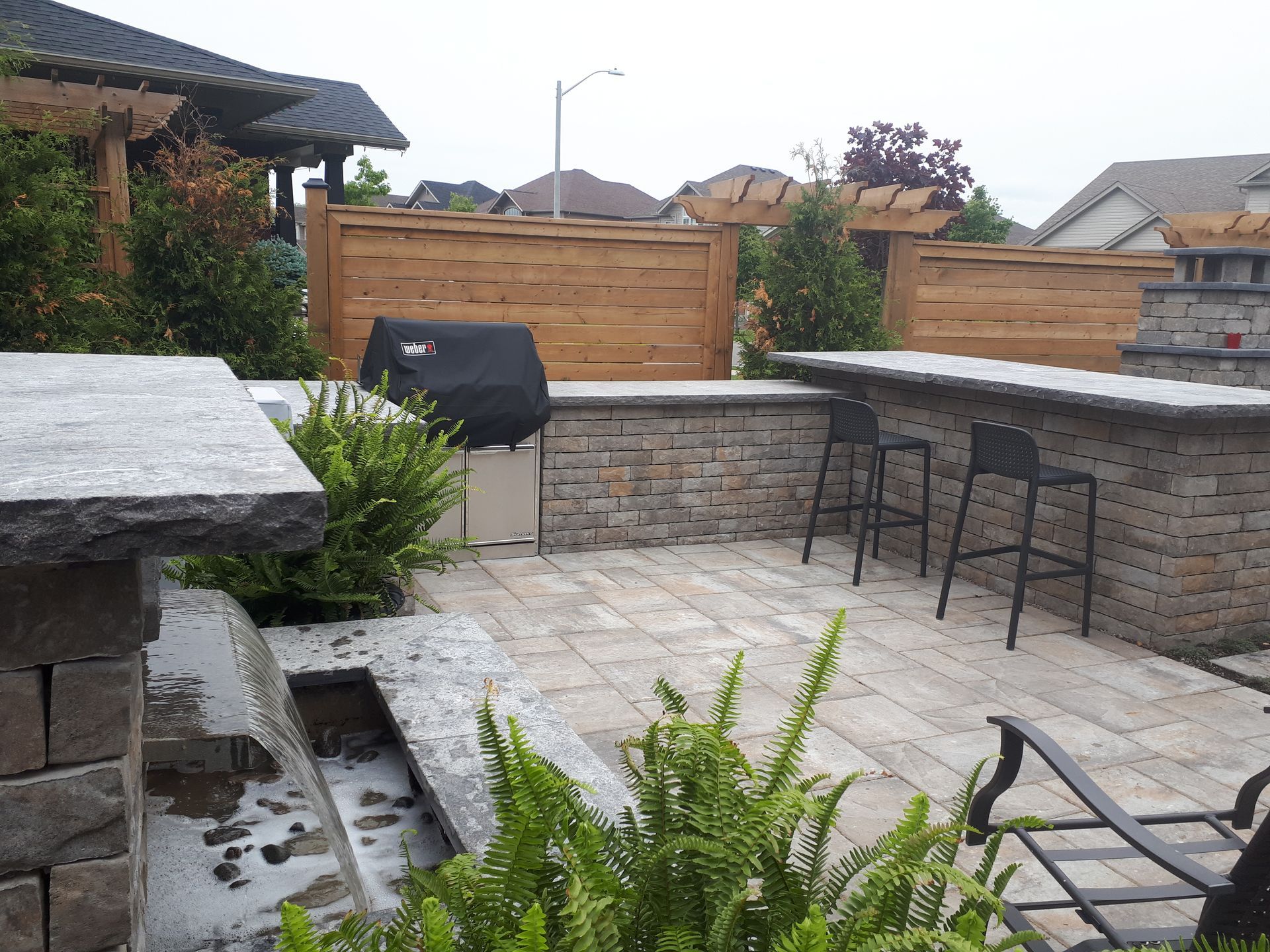 A brick patio with a grill and stools