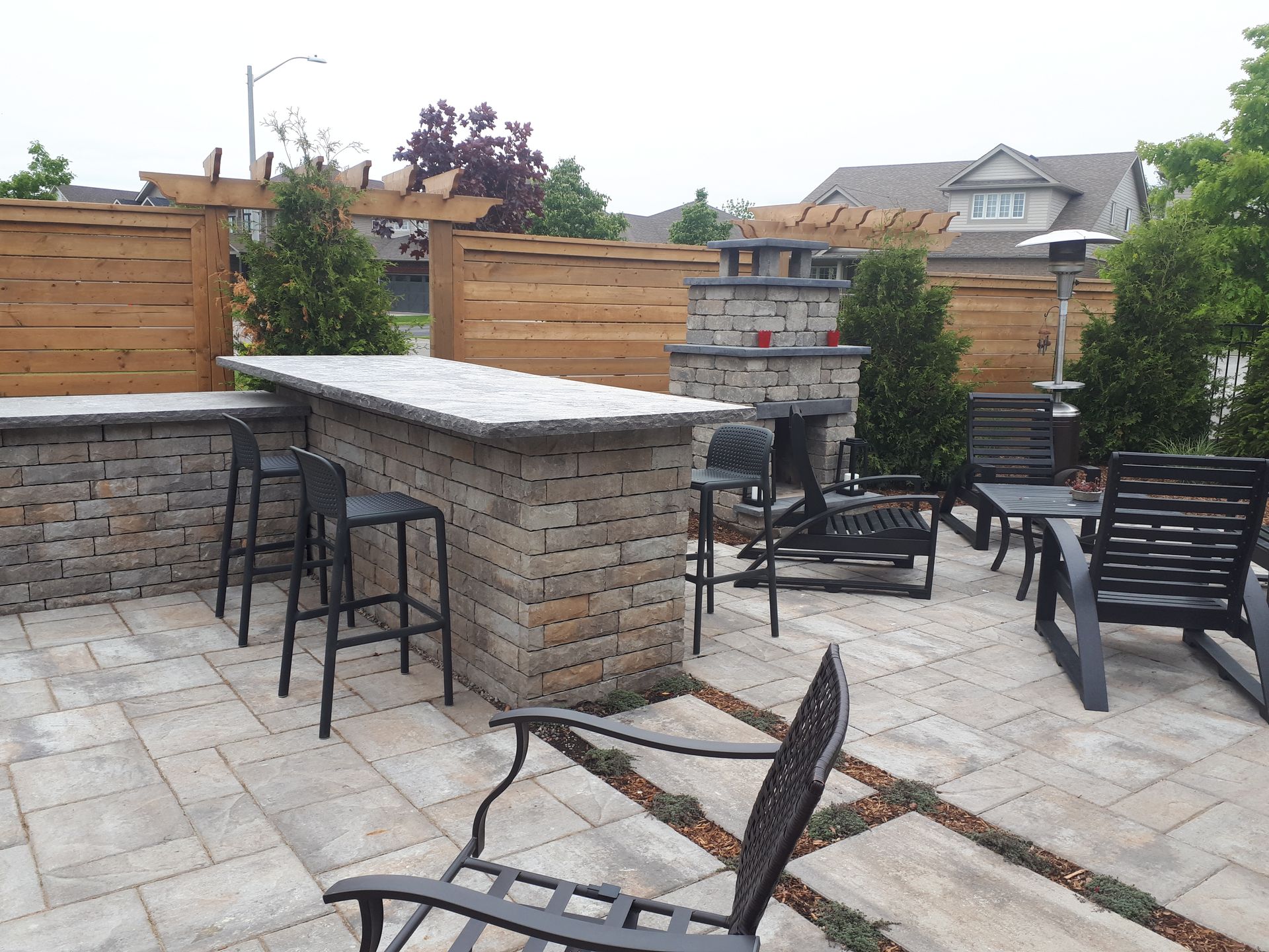 A patio with a bar and chairs and a fireplace