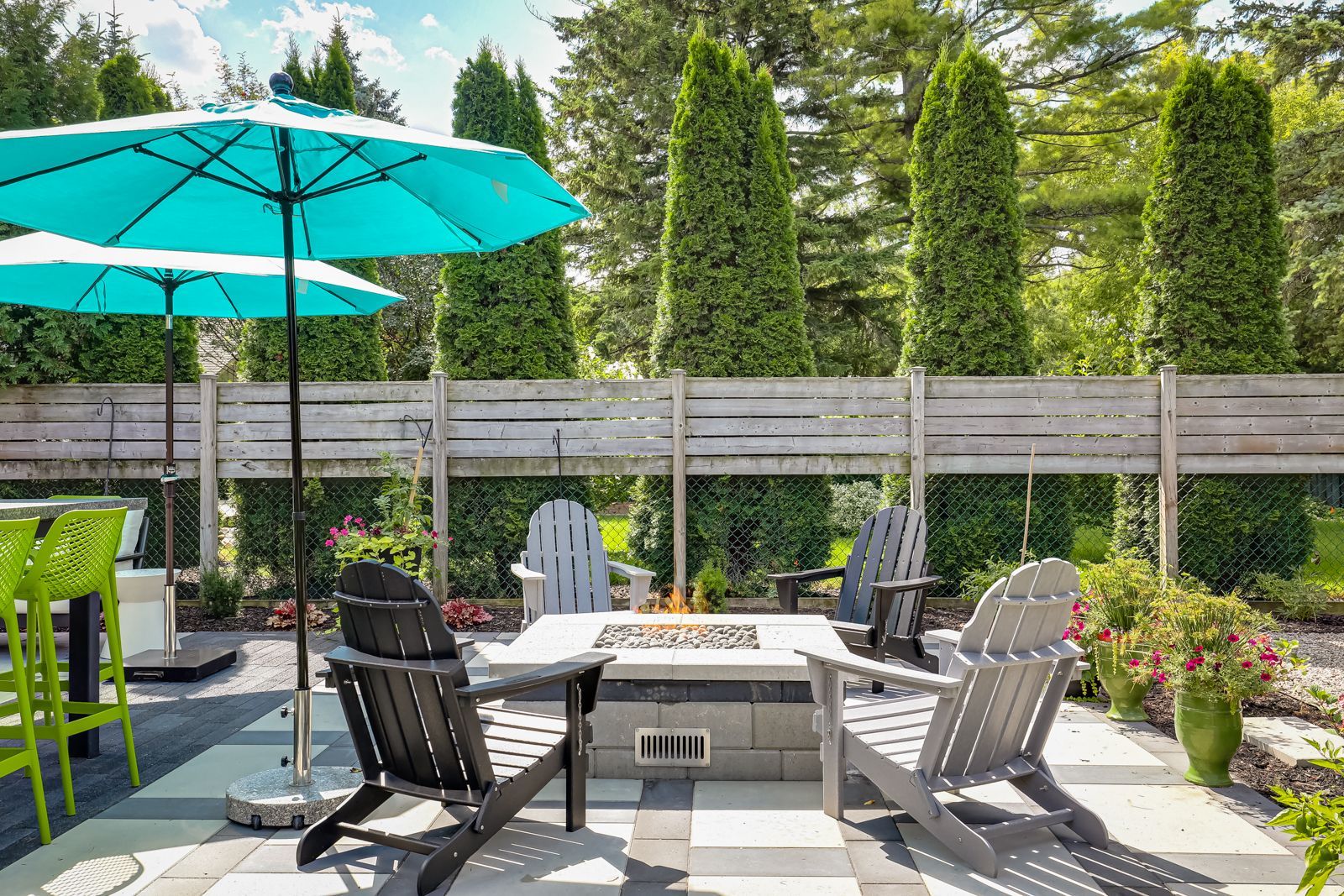 There is a fire pit in the backyard with chairs and umbrellas.