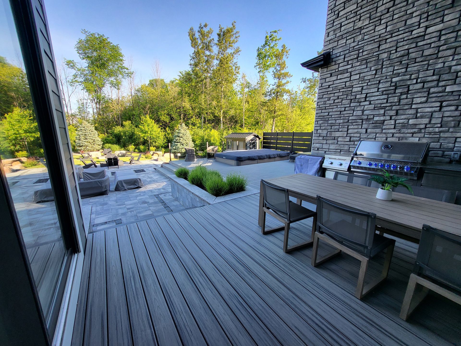 A wooden deck with a table and chairs and a grill.