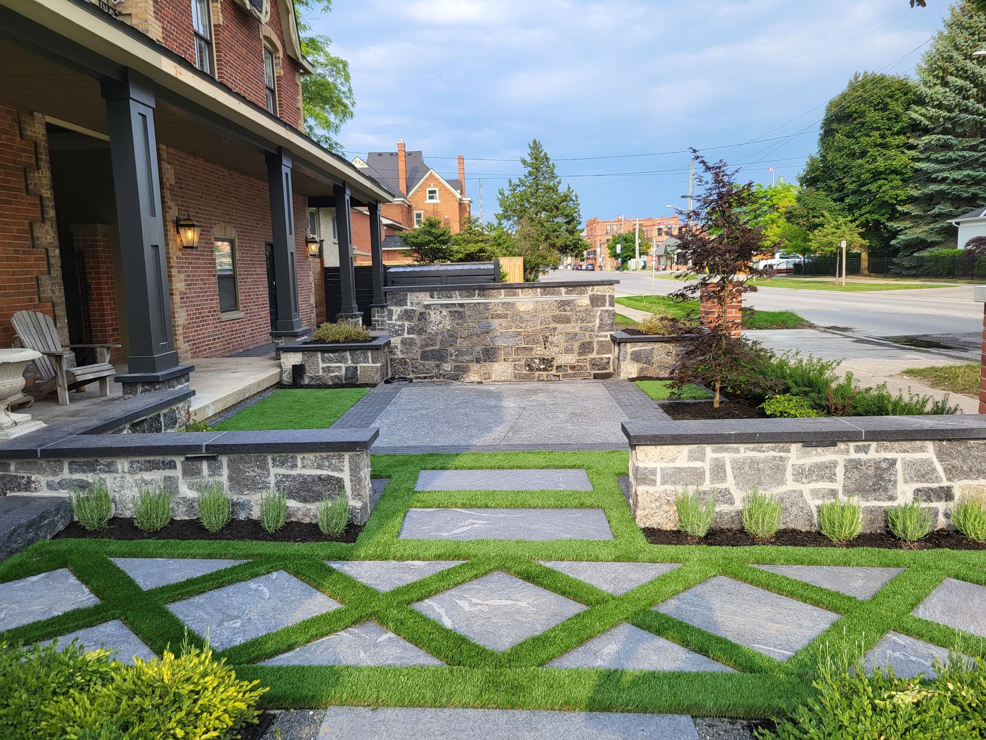 A brick house with a stone wall and a walkway in front of it.