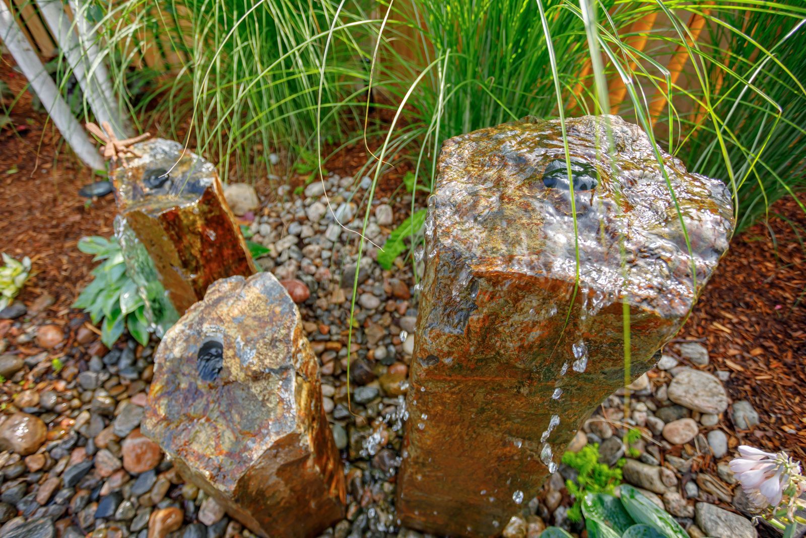 A water fountain is surrounded by rocks and plants in a garden.