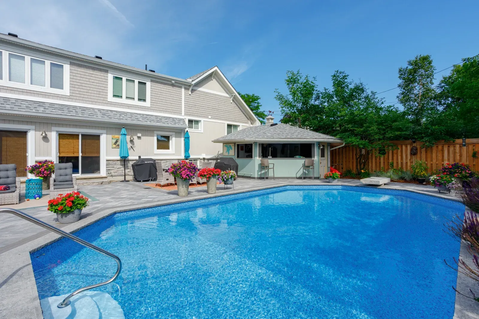There is a large swimming pool in the backyard of a house.