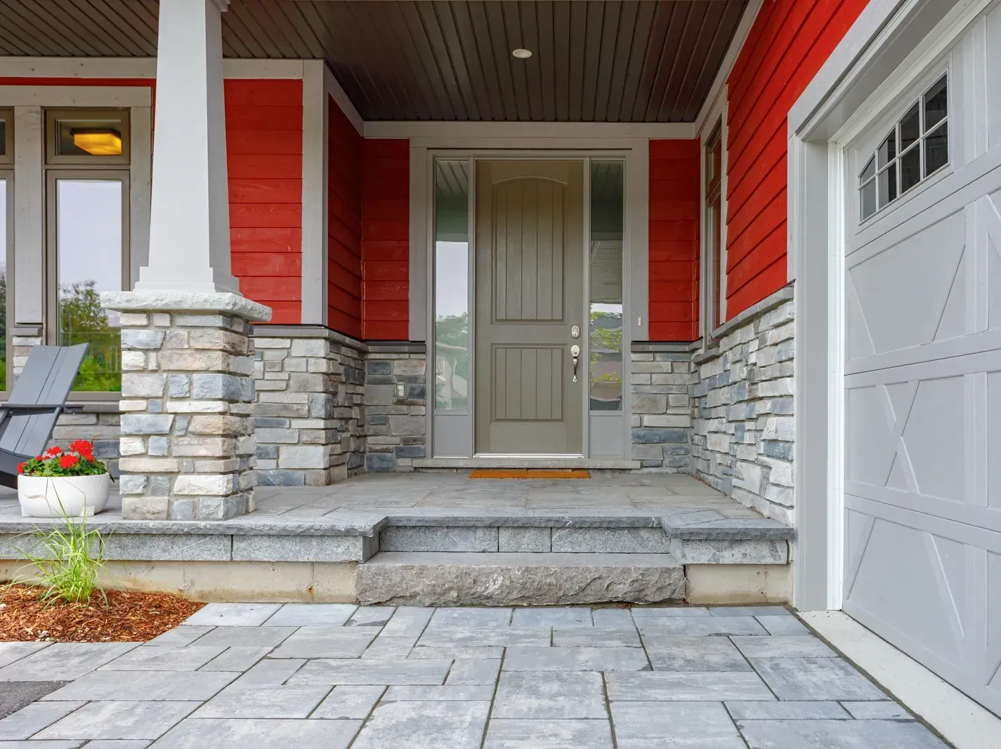The front porch of a red house with a garage door.