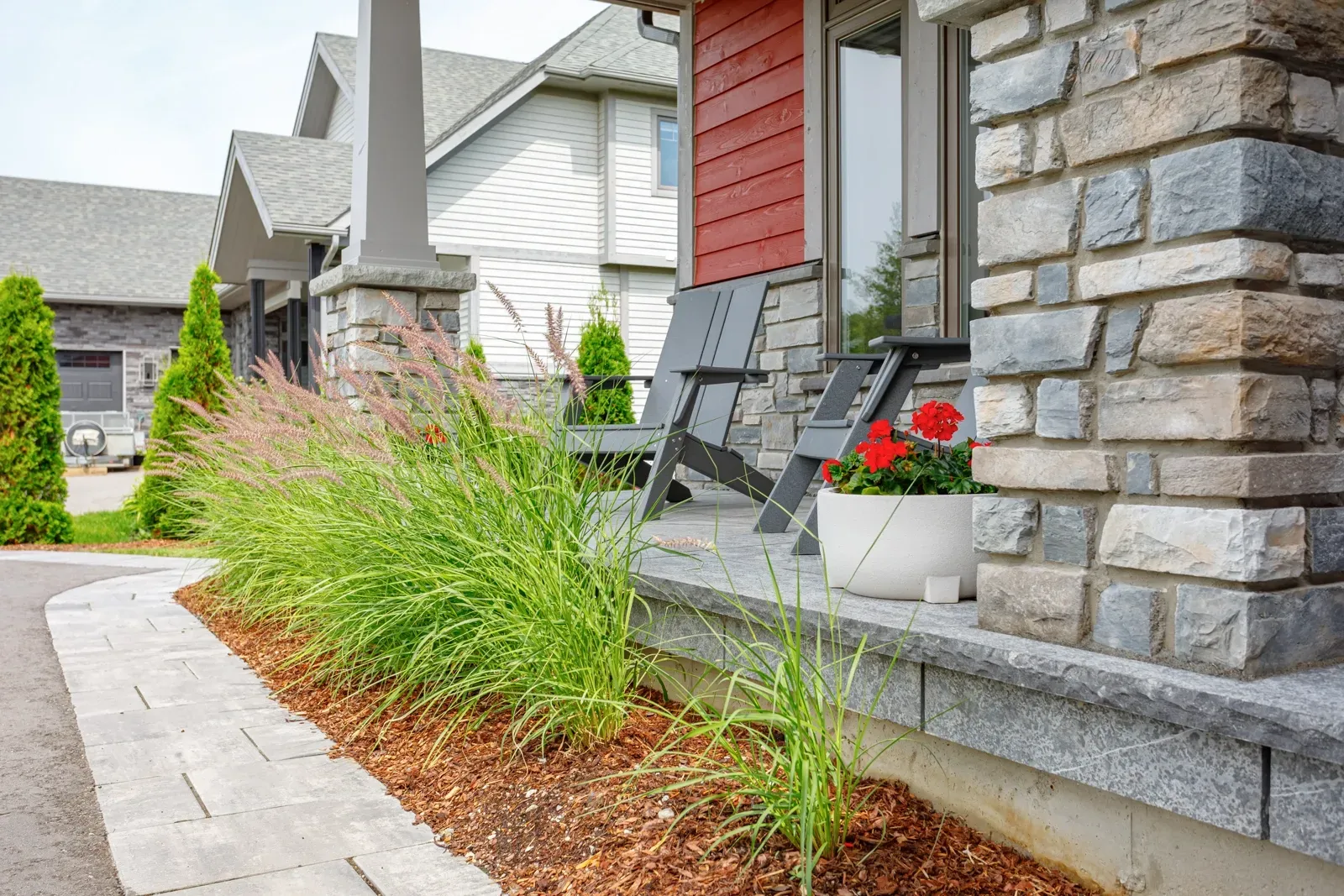 A stone house with a porch and chairs in front of it.