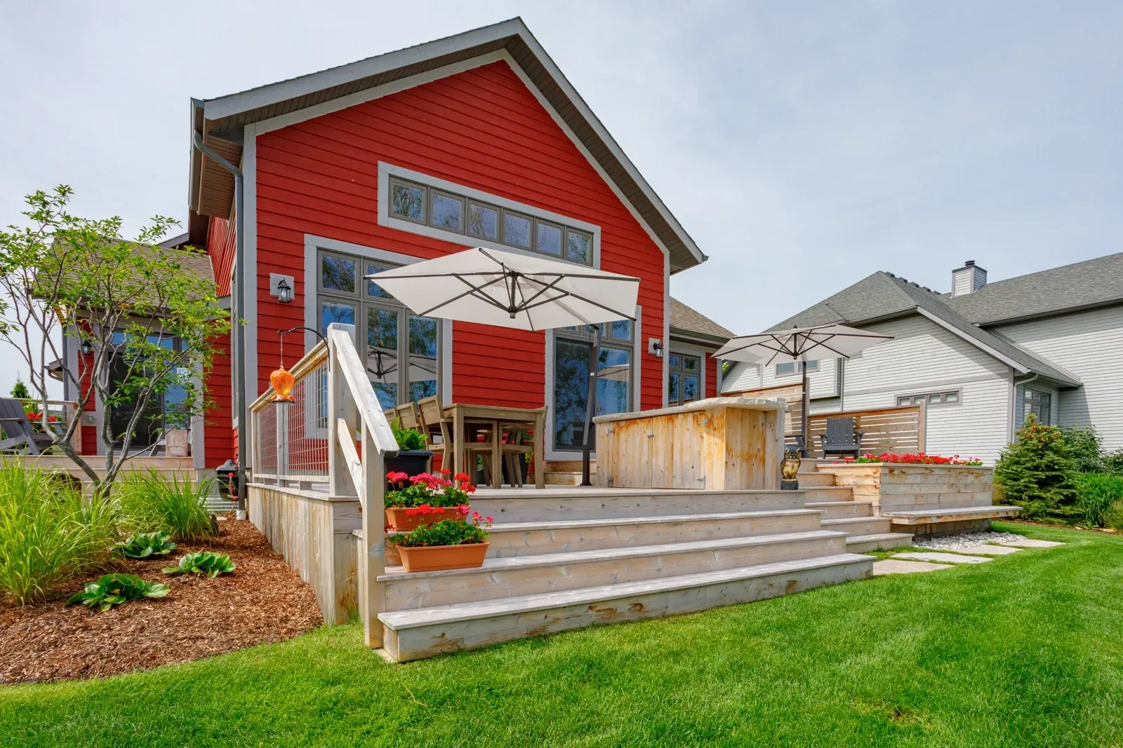 A red house with a patio and umbrella in front of it.