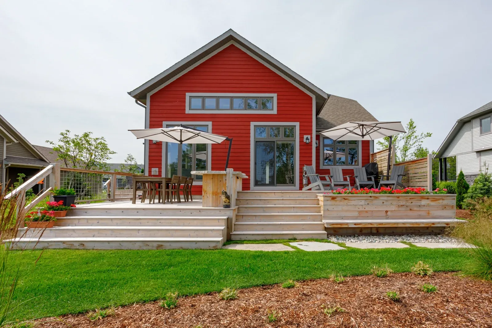A red house with a deck and umbrellas in front of it.