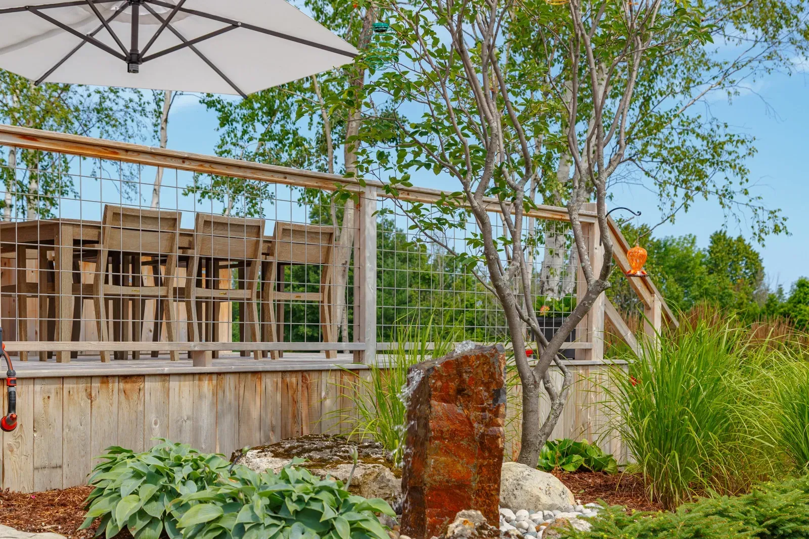 A patio with a table and chairs , a fountain , and an umbrella.
